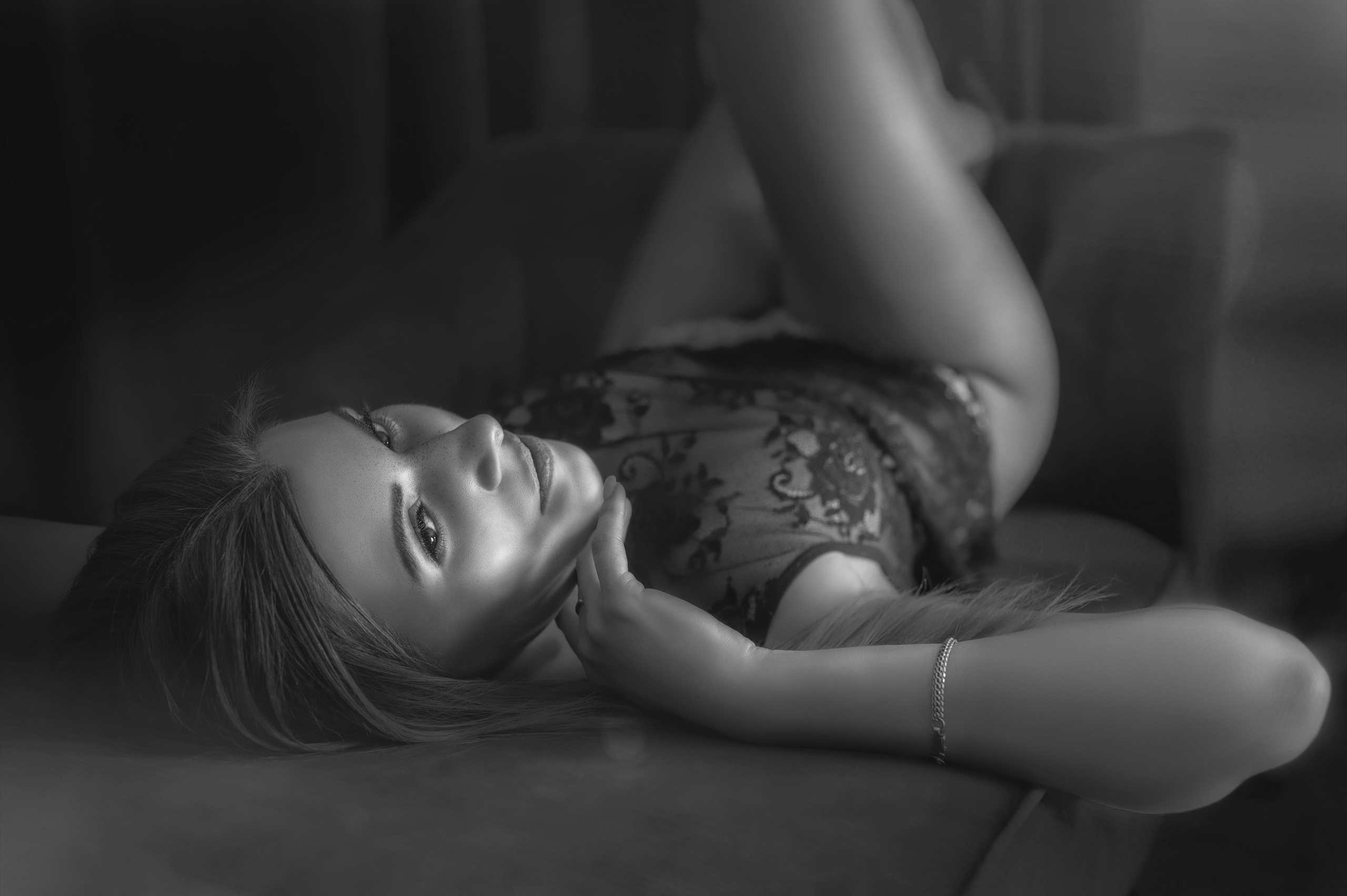 Девушка в кружевном черном боди лежит на спине