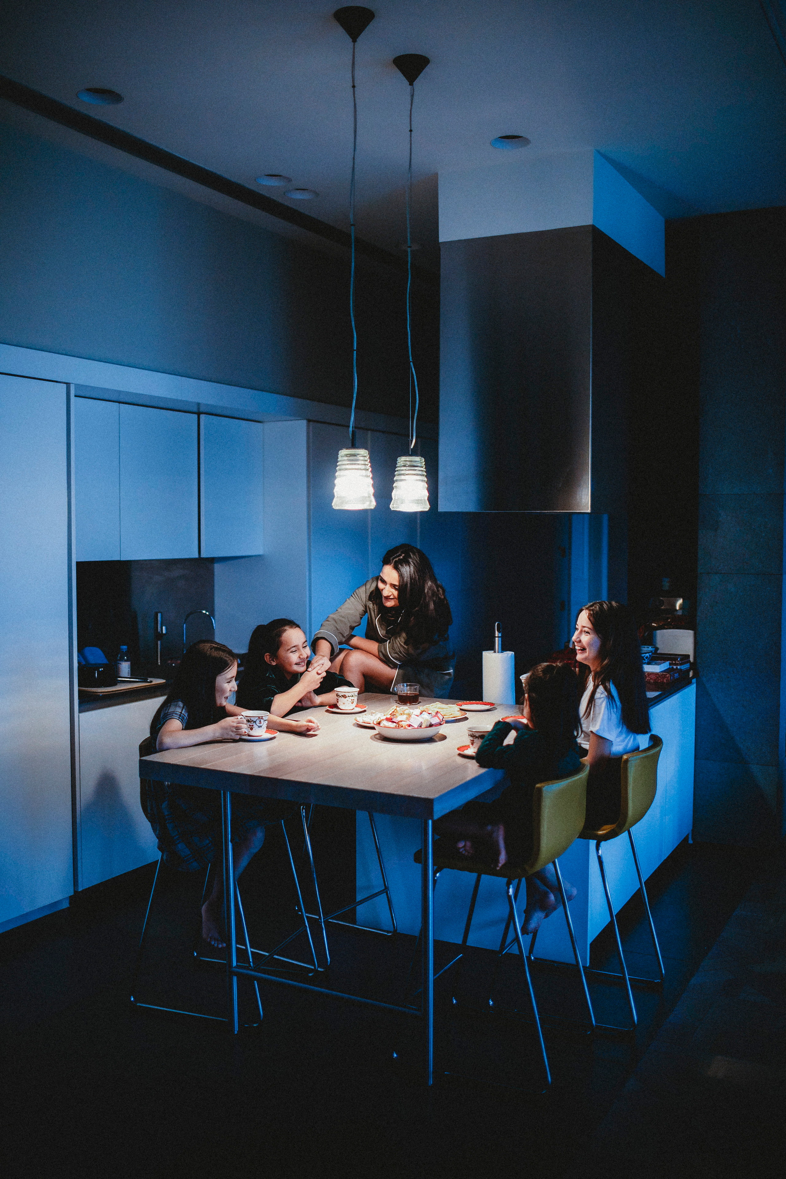  Мама со своими детьми дома за обеденным столом пьют чай зимой