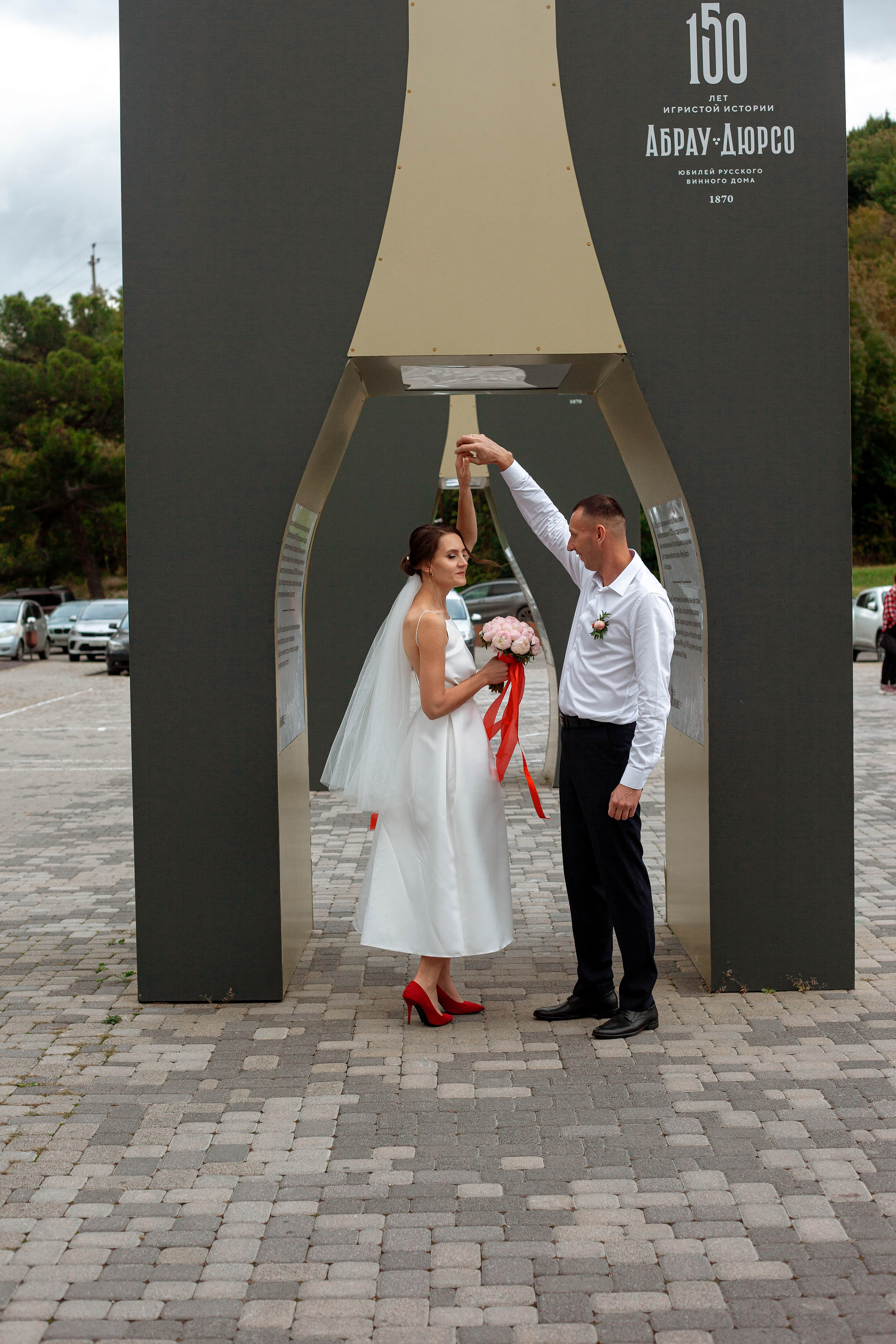 жених крутит невесту в белом платье и с букетом