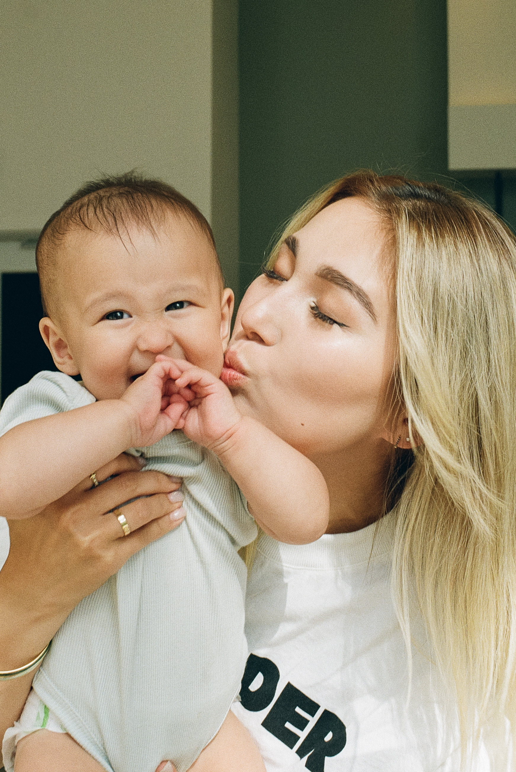 a mother kissing her laughing baby who just turned one