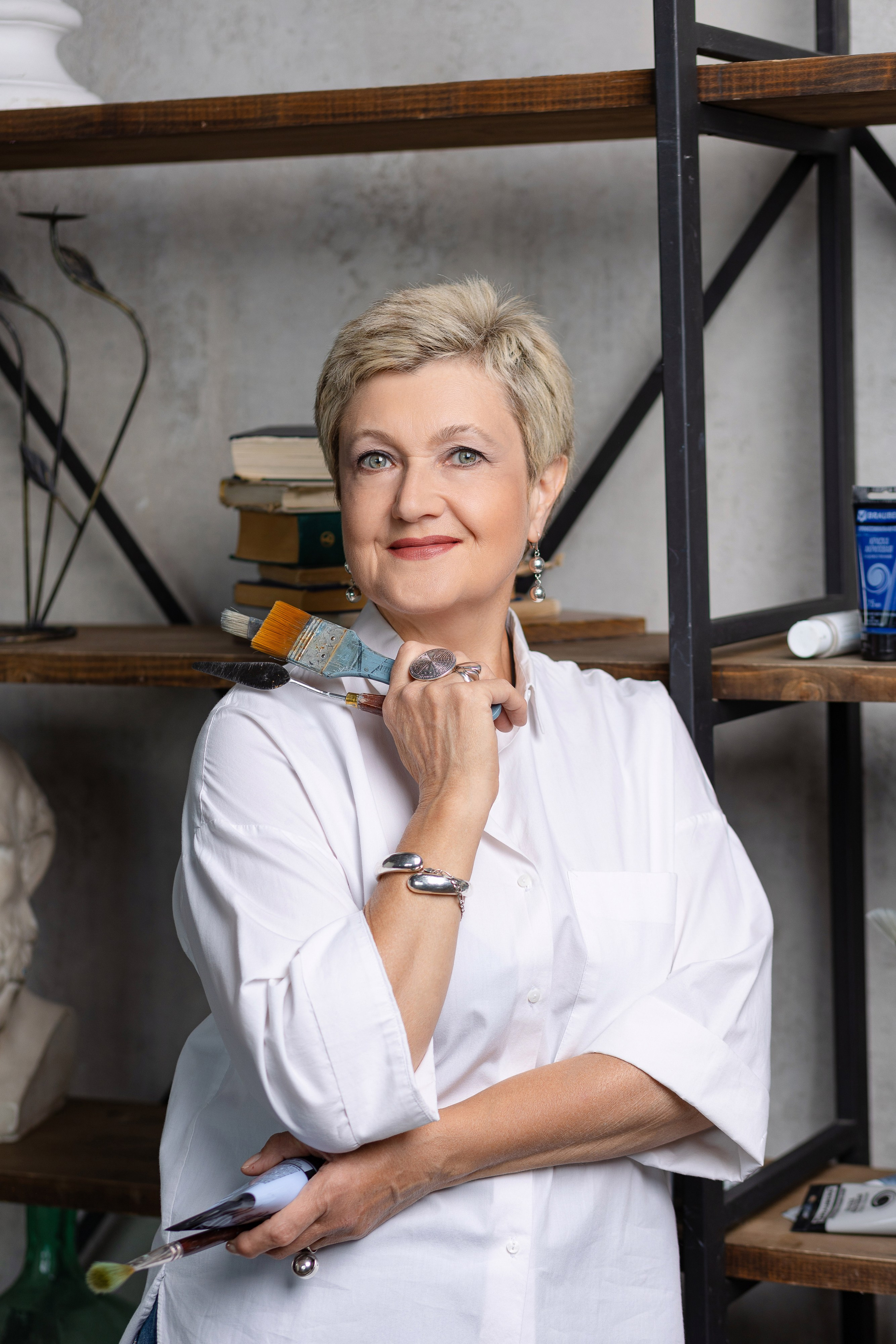 Женщина художница держит в руках тюбике с краской и кисти