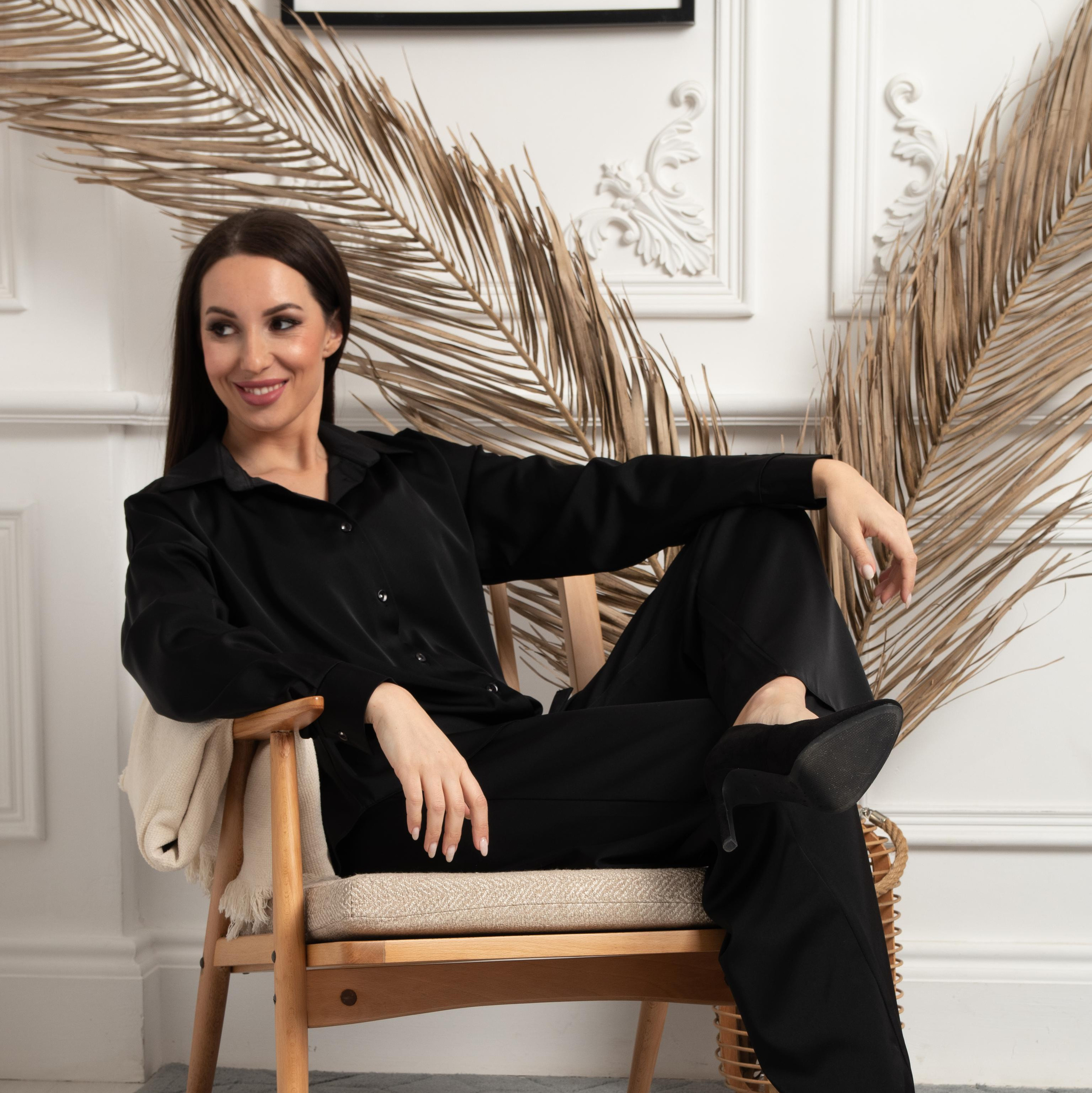 Девушка модель в черном брючном костюме в кресле