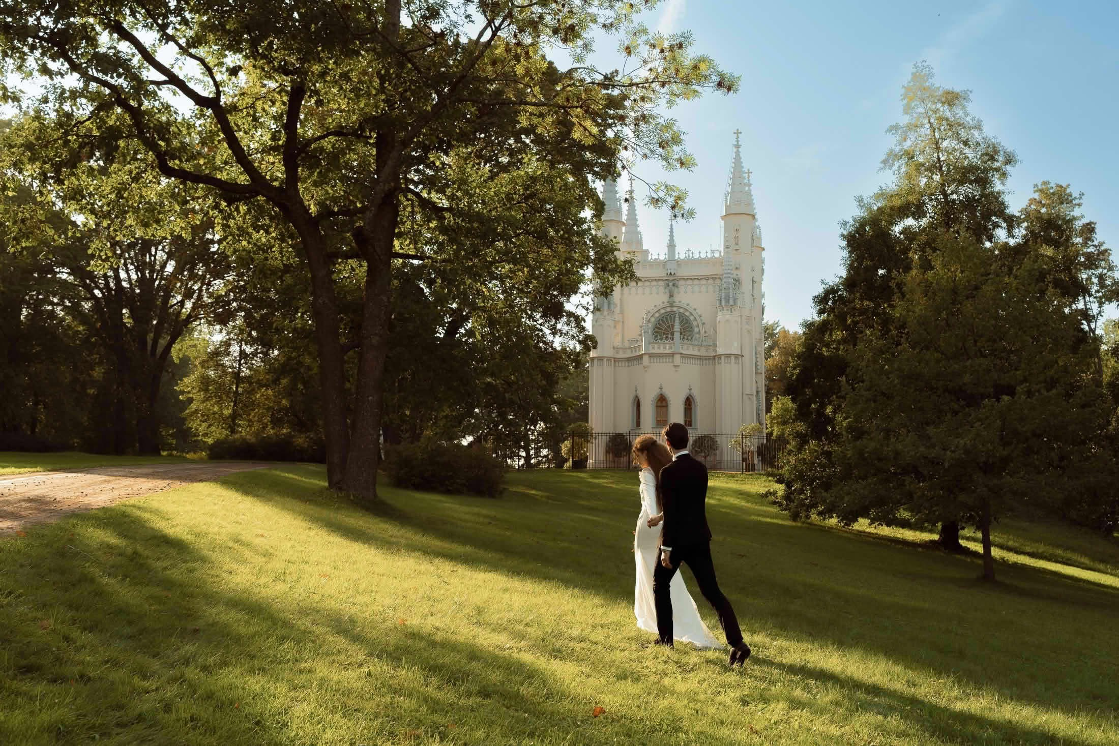 Жених и невеста в парке у готической капеллы в пригороде Петербурга