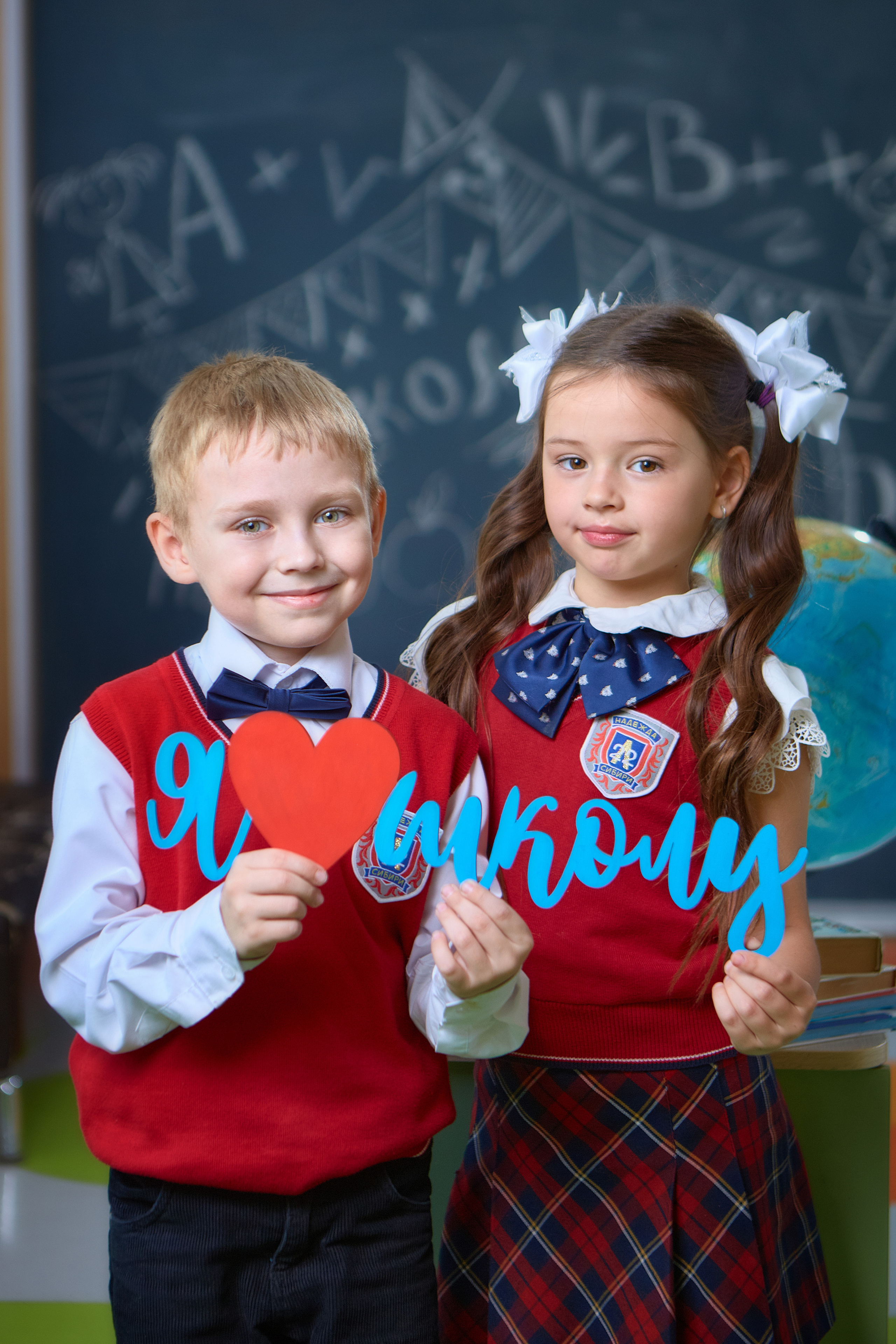 Мальчик и девочка друзья первоклассники и соседи по парте держат надпись я люблю школу