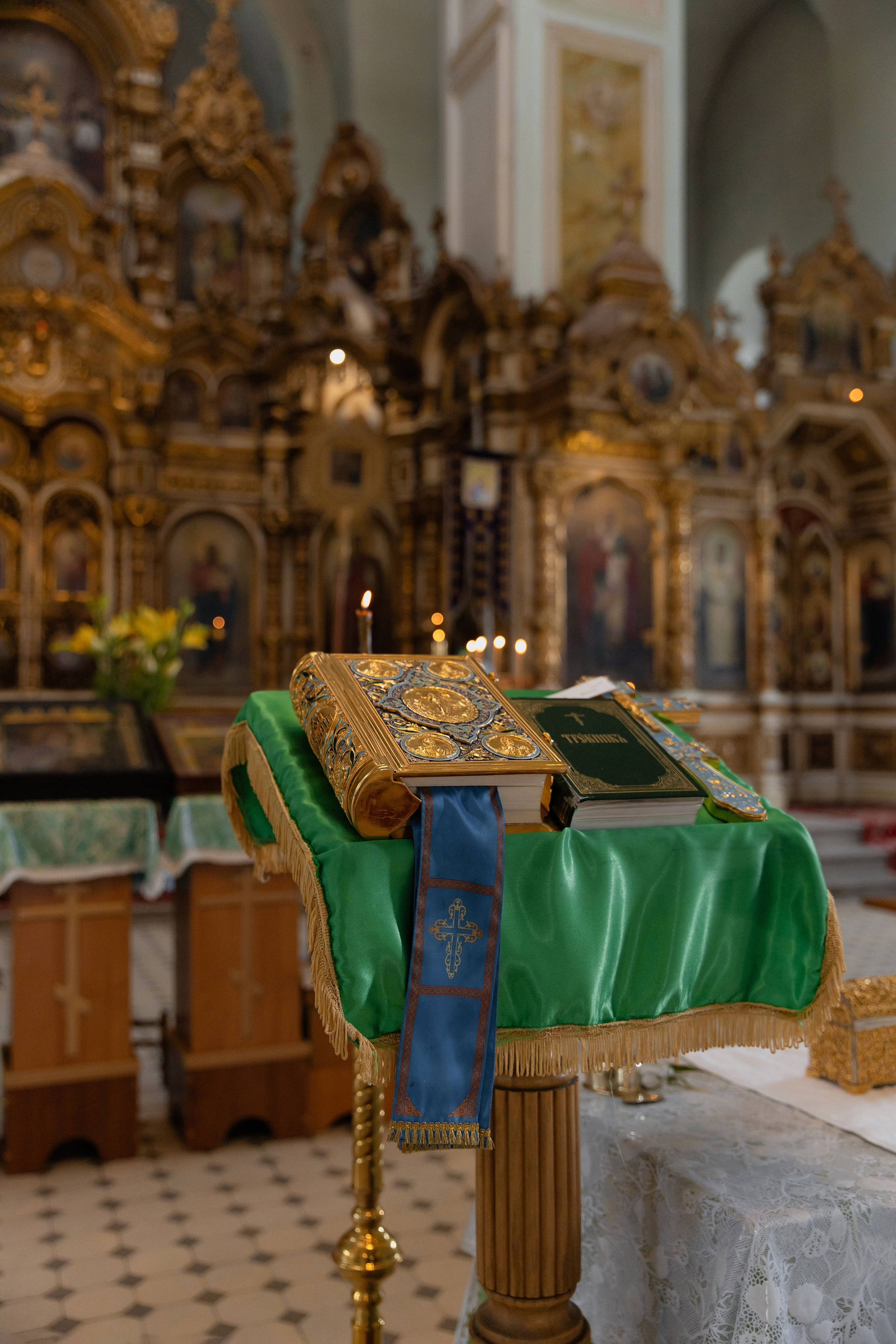 Фотография таинства крещения малыша: Священная Библия лежит на аналое, укрытой зеленой материей, на фоне алтаря церкви Успения Пресвятой Богородицы в г. Донецк Ростовской области