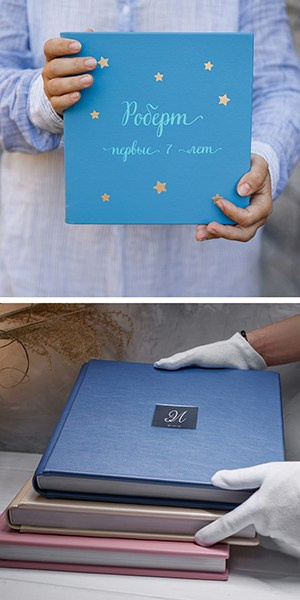 Детская фотокнига из голубой кожи с золотыми звездами и стопка премиальных кожаных альбомов в руках мастера в белых перчатках.