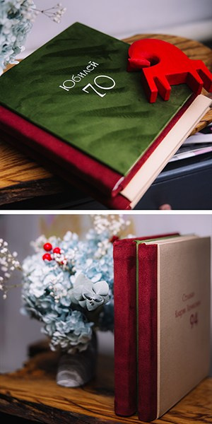 Верхнее фото: темно-зеленая бархатная книга с надписью «Юбилей 70», на которой стоит деревянная фигурка красной лошади "Конь Огонь". Нижнее фото: две книги в бордовом бархате стоят вертикально, демонстрируя фактуру ткани и лаконичное тиснение на обложке.