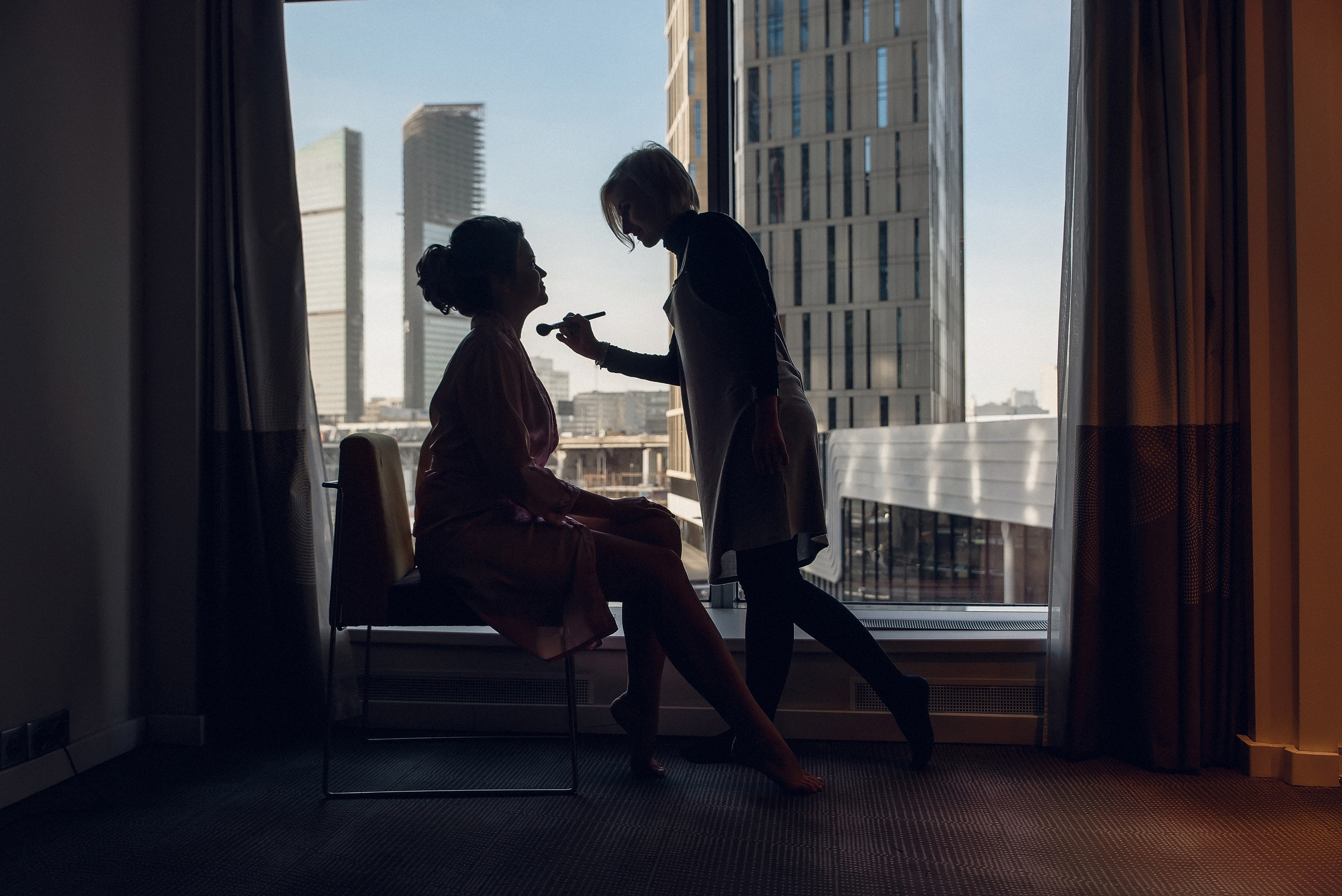 Силуэт невесты со стилистом  на фоне Москва-сити. утро невесты в отеле Свадебный фотограф в Москве Сергей Гаварос 