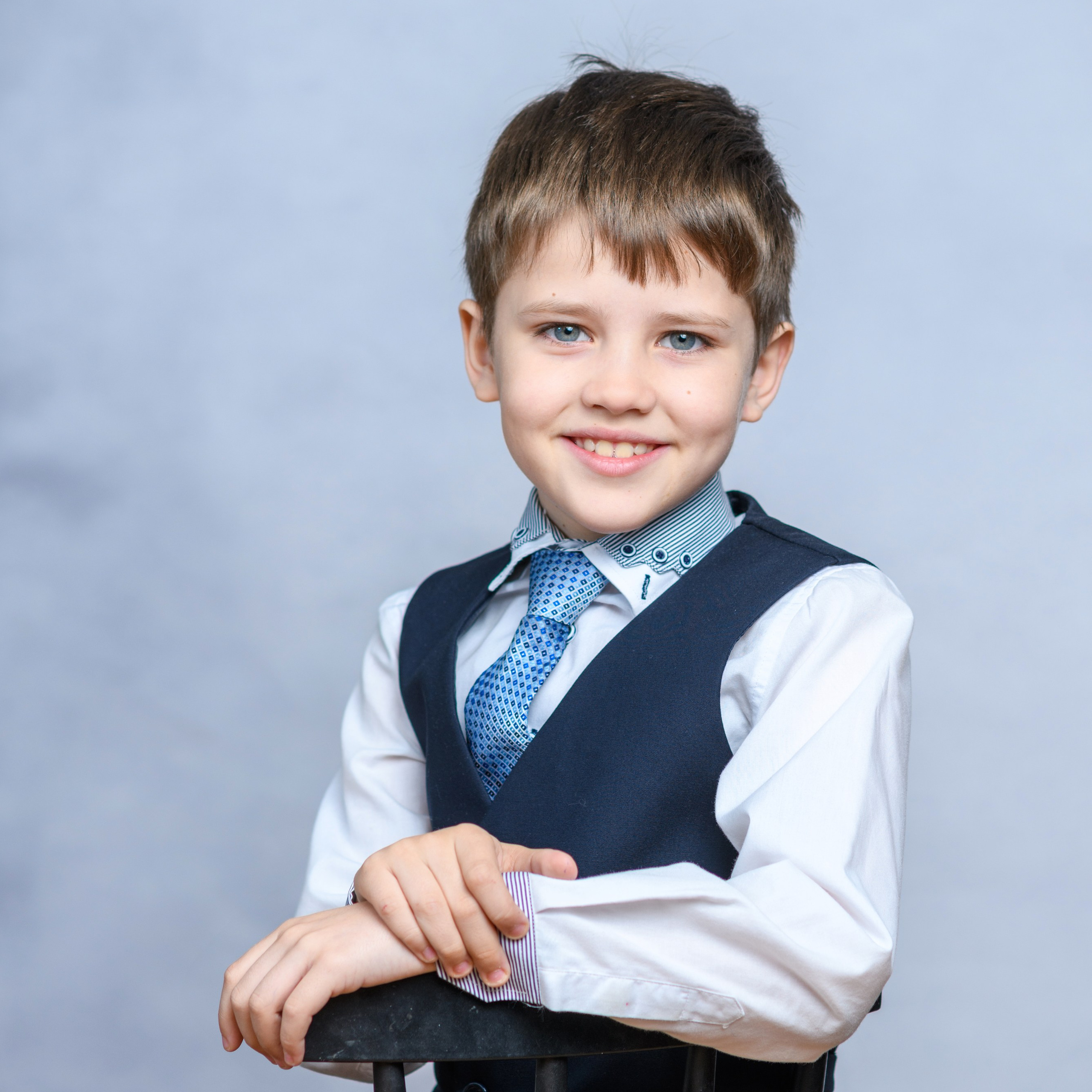 Школьная фотосессия. Портрет мальчика первоклассника на сером фоне.