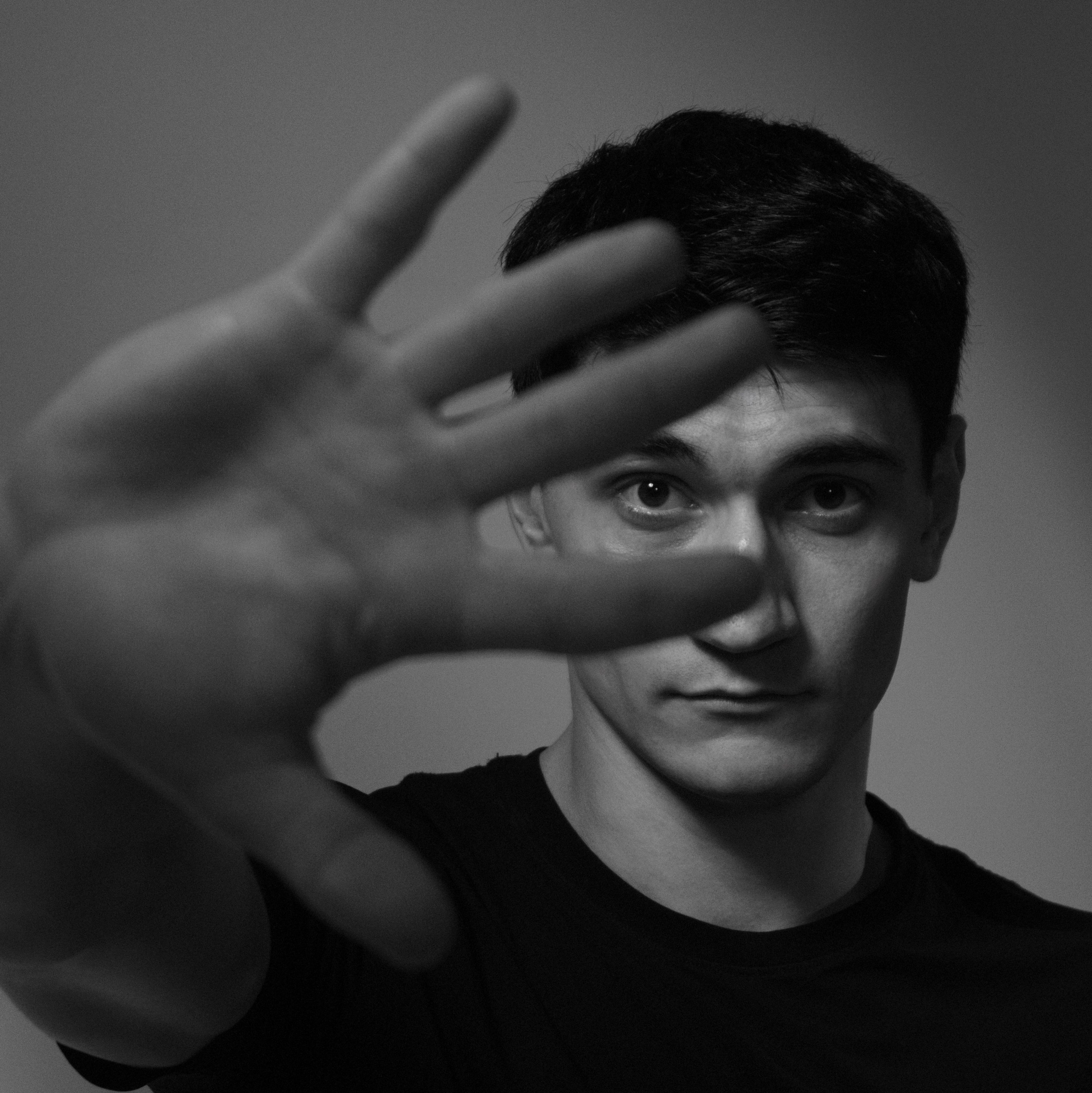чёрно-белый портрет человека с рукой перед лицом, эмоциональная студийная фотография, контрастный свет