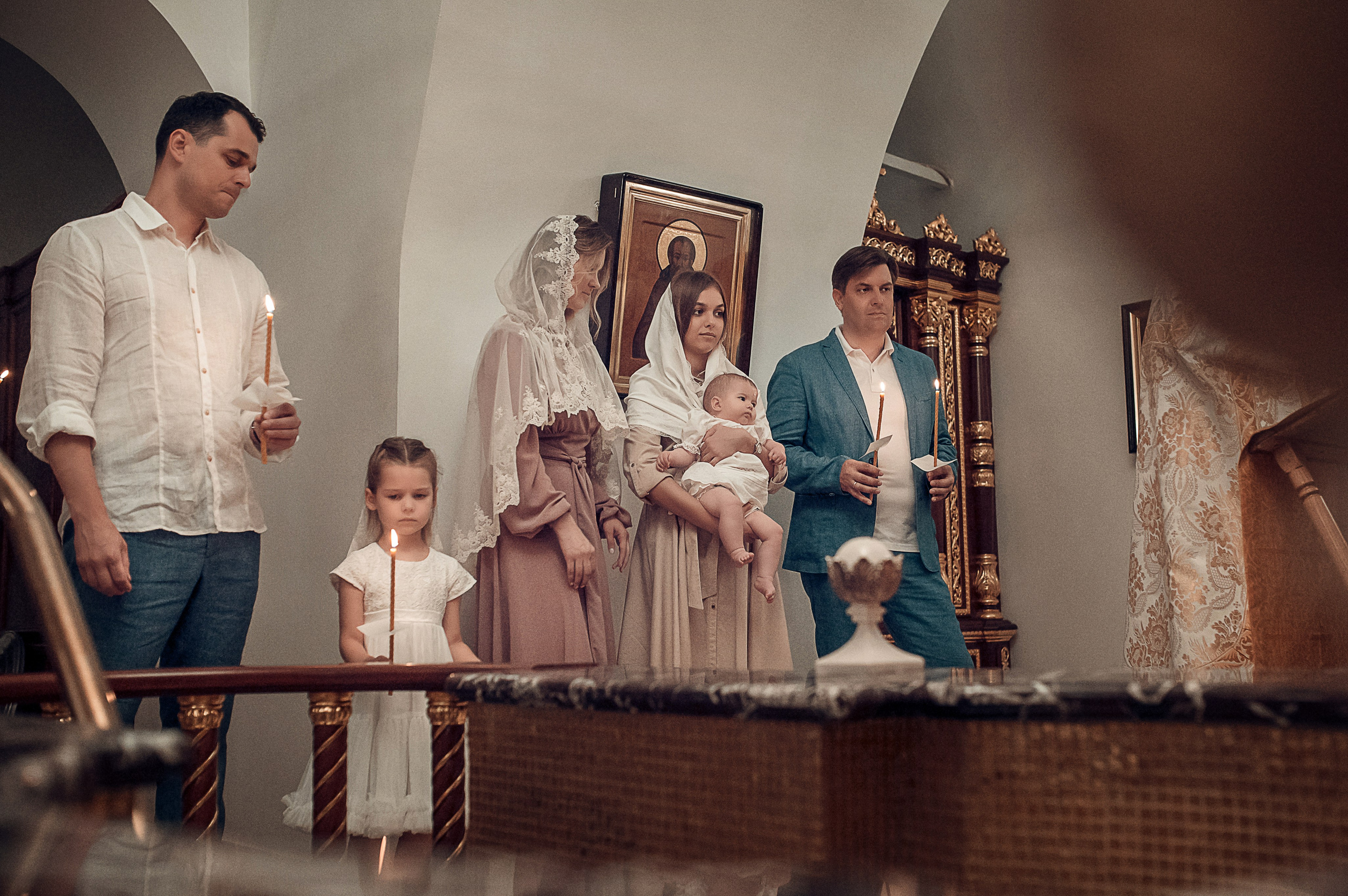 Профессиональная видеосъемка венчания и крещения в Москве: таинство в православном храме Красивая видеосъемка крещения ребенка в церкви Москвы: крупный план младенца и священника  Видеосъемка обряда венчания в храме: молодожены держат венцы над головами Услуги видеографа на крестины и венчание в Москве: эмоциональный кадр церемонии