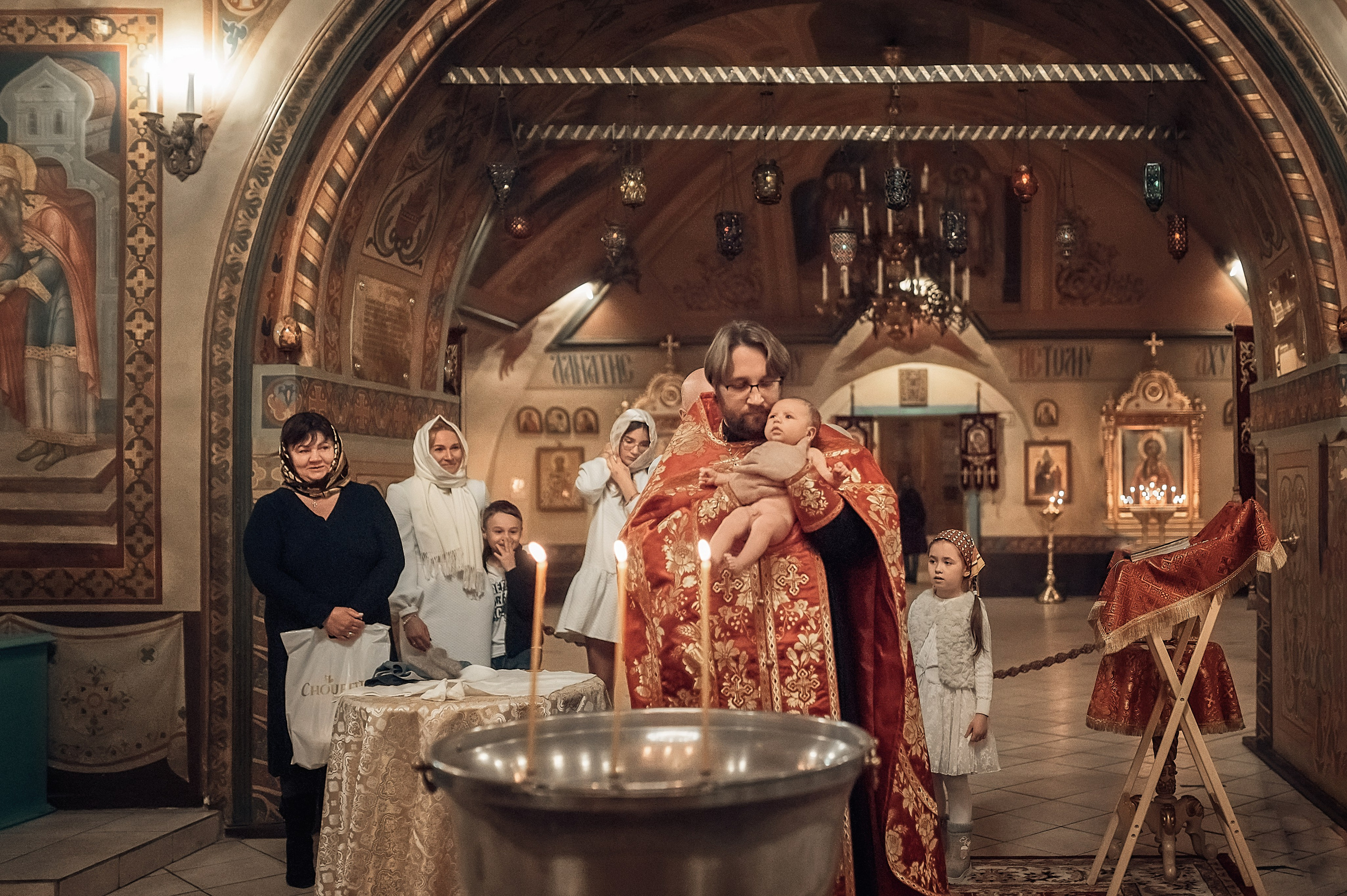 Профессиональная видеосъемка венчания и крещения в Москве: таинство в православном храме Красивая видеосъемка крещения ребенка в церкви Москвы: крупный план младенца и священника  Видеосъемка обряда венчания в храме: молодожены держат венцы над головами Услуги видеографа на крестины и венчание в Москве: эмоциональный кадр церемонии