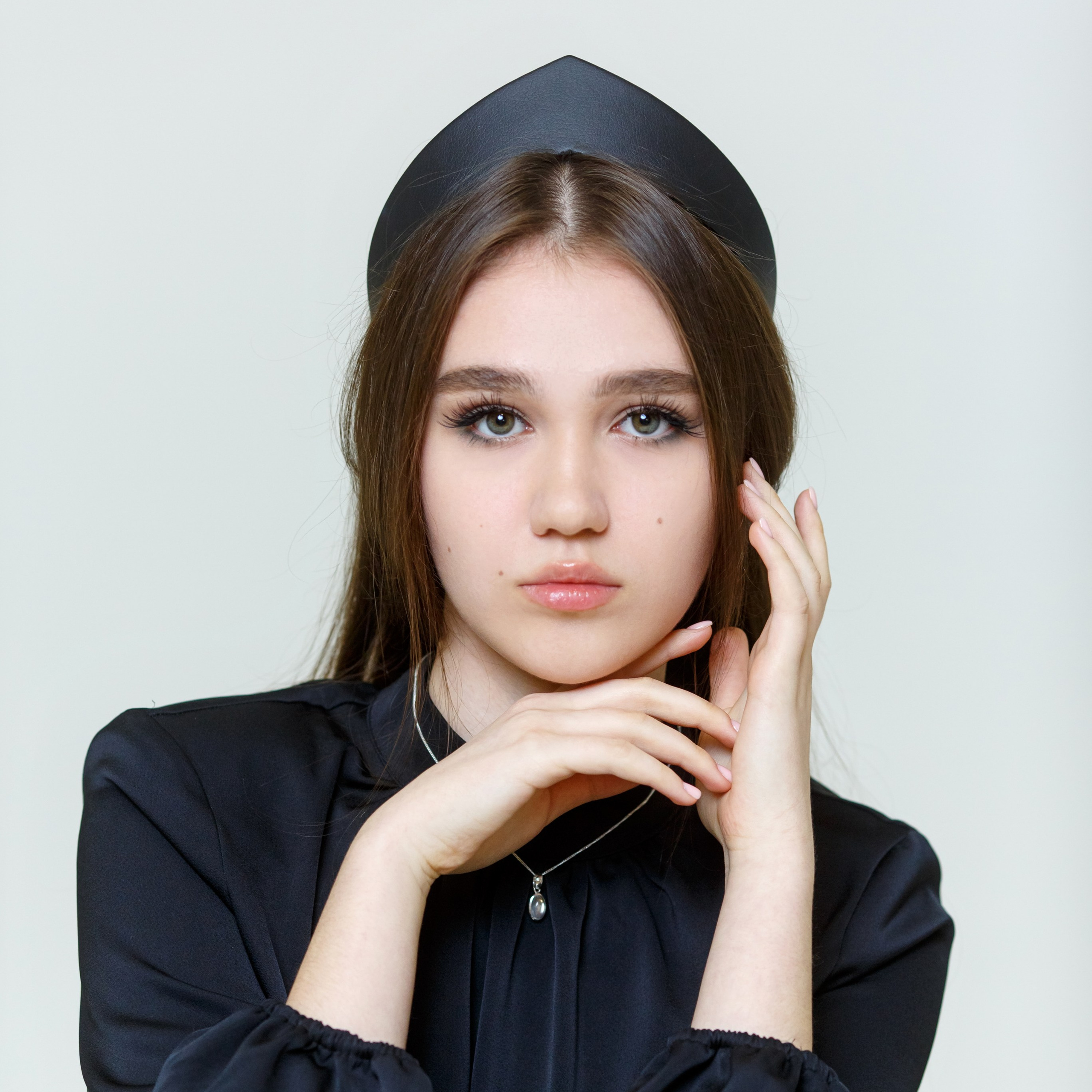 Выпускница сидит на кресле нагнув корпус вперёд. Работа школьного фотографа фотостудии Вышка в Москве.