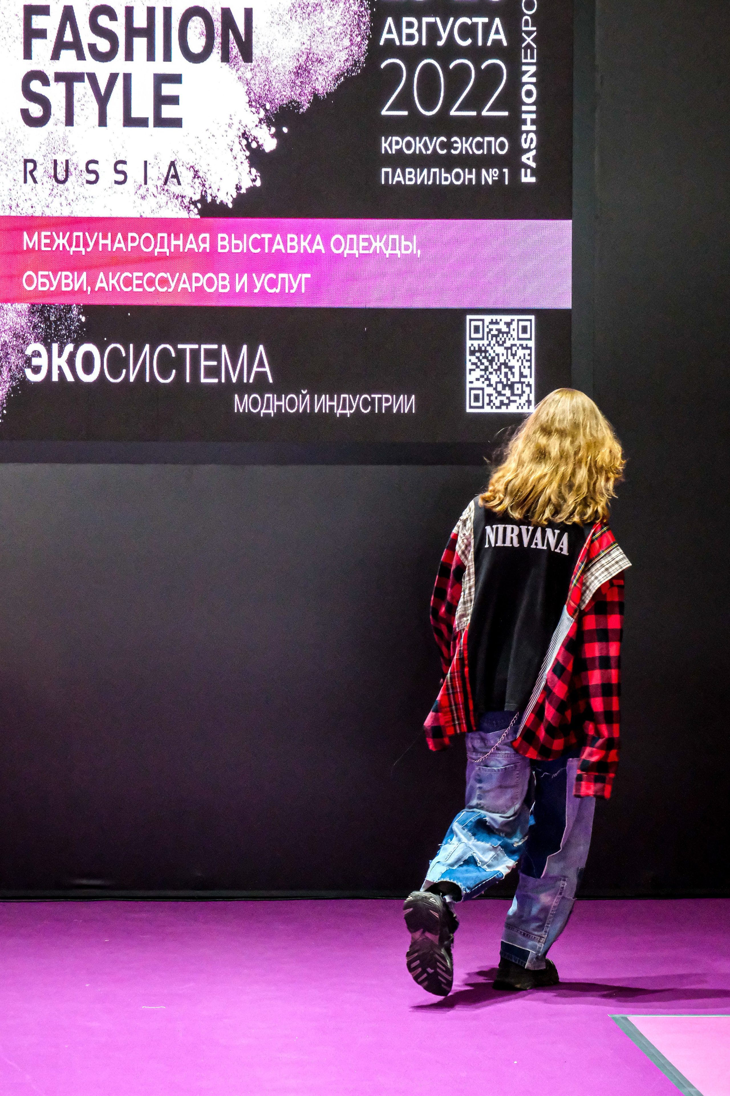  "Модели в ярких нарядах проходят по подиуму во время показа мод, освещенные яркими софитами и окруженные восторженными зрителями."