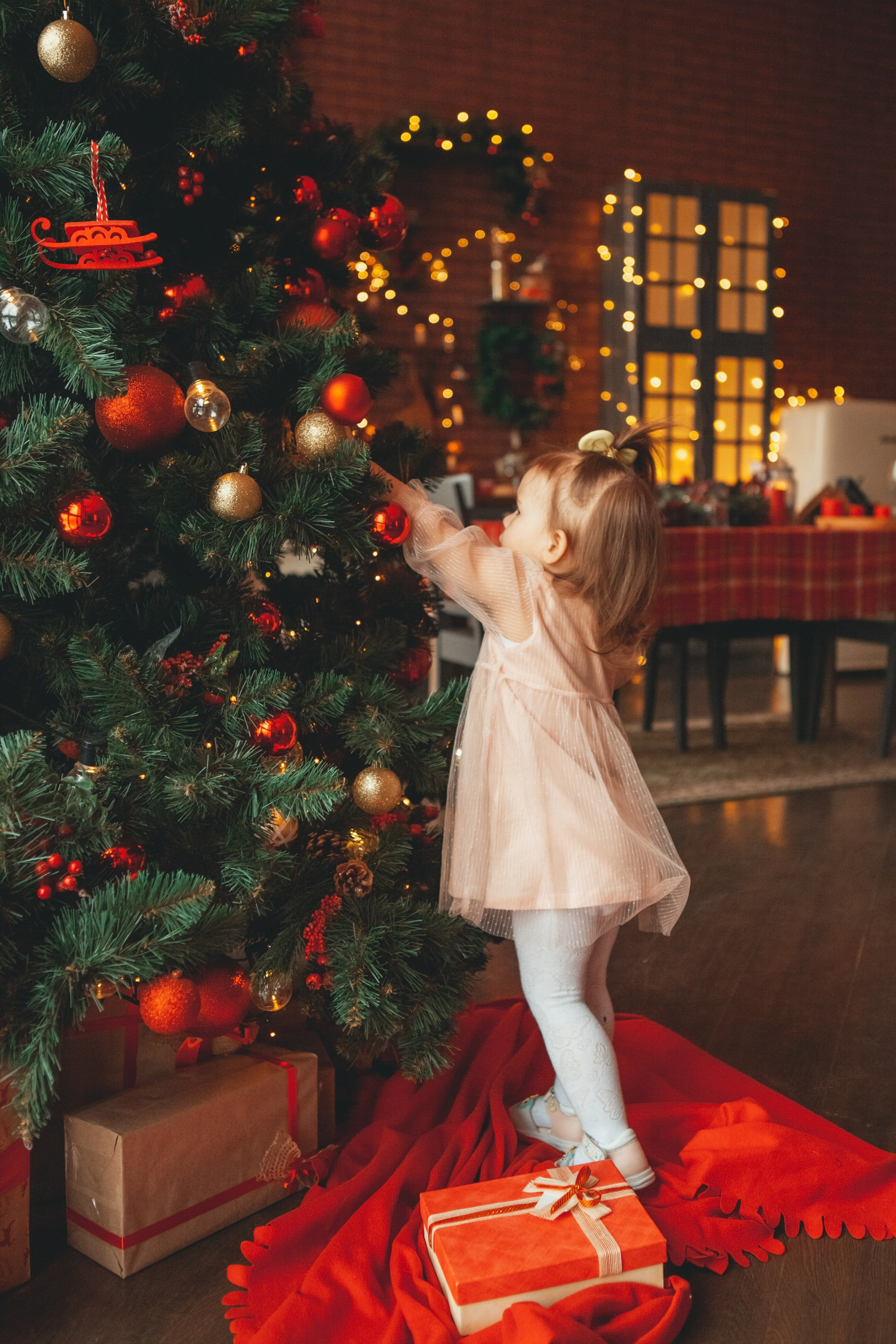 маленькая девочка вешает новогодние игрушки на ёлку
