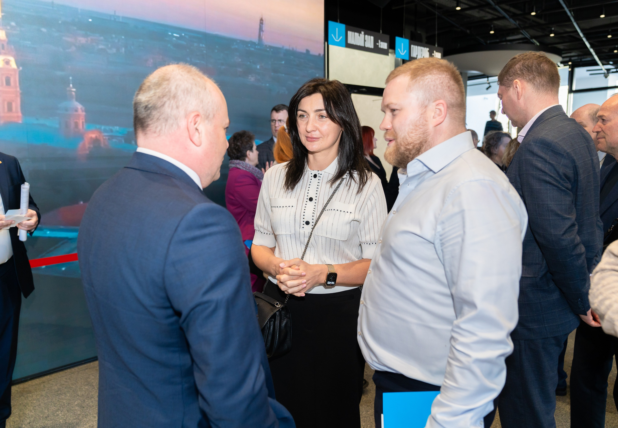 Деловое общение на Дне местного самоуправления Санкт-Петербург. Женщина в белой блузке в разговоре с коллегами. Фото Евгения Мальцева.