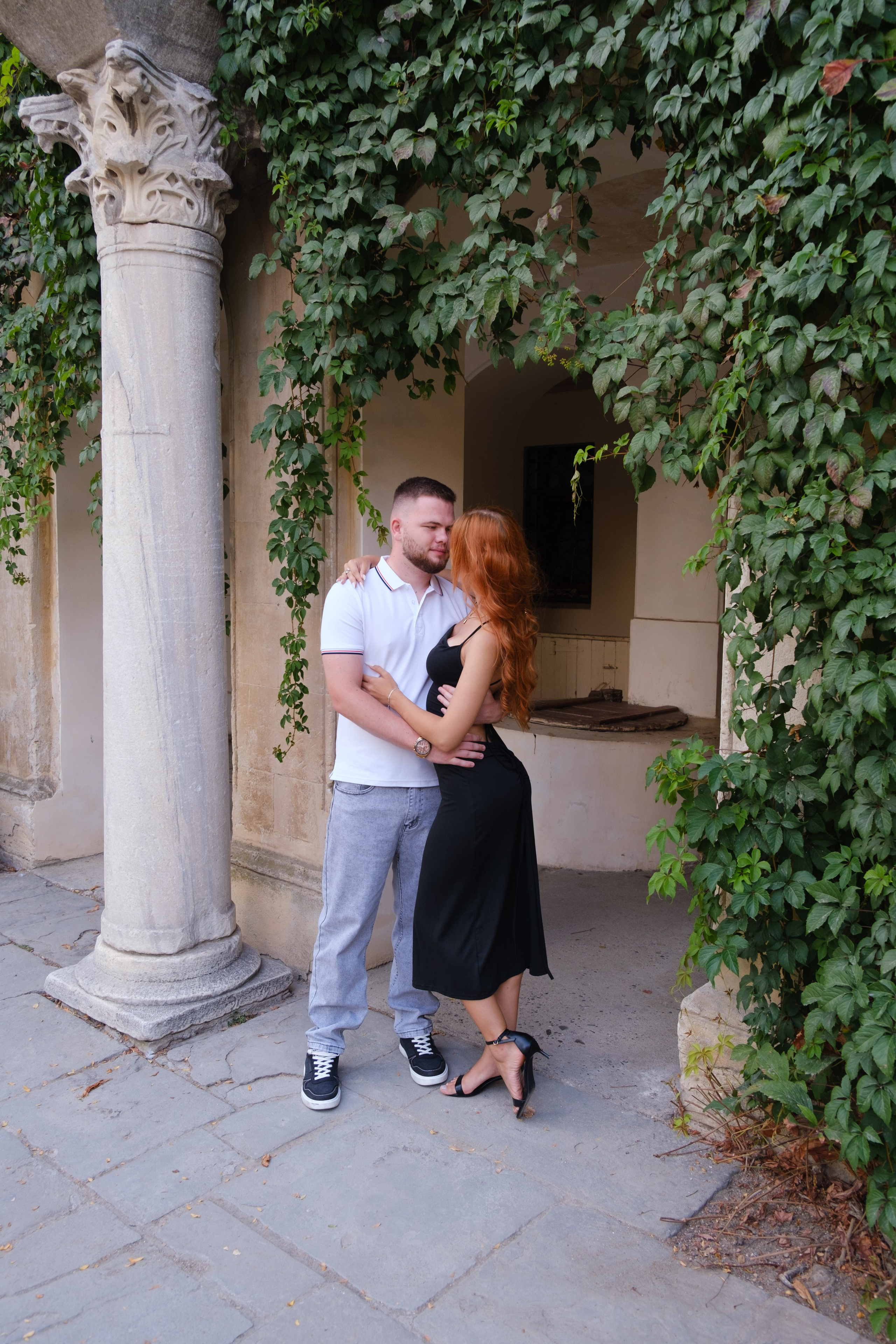 Прекрасная пара обнимается в арке зелёных кустов в итальянском дворике Херсонеса таврического. Фотограф и видеограф Желдак Илья