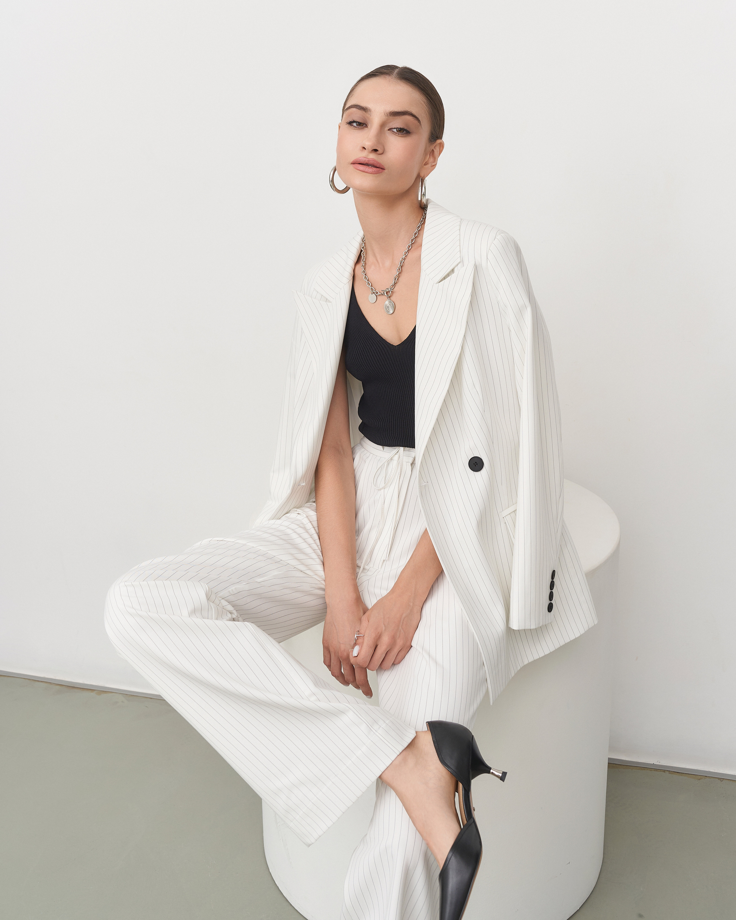 Неформальный лук: костюм с расстегнутым пиджаком, модель сидит, скрестив ноги