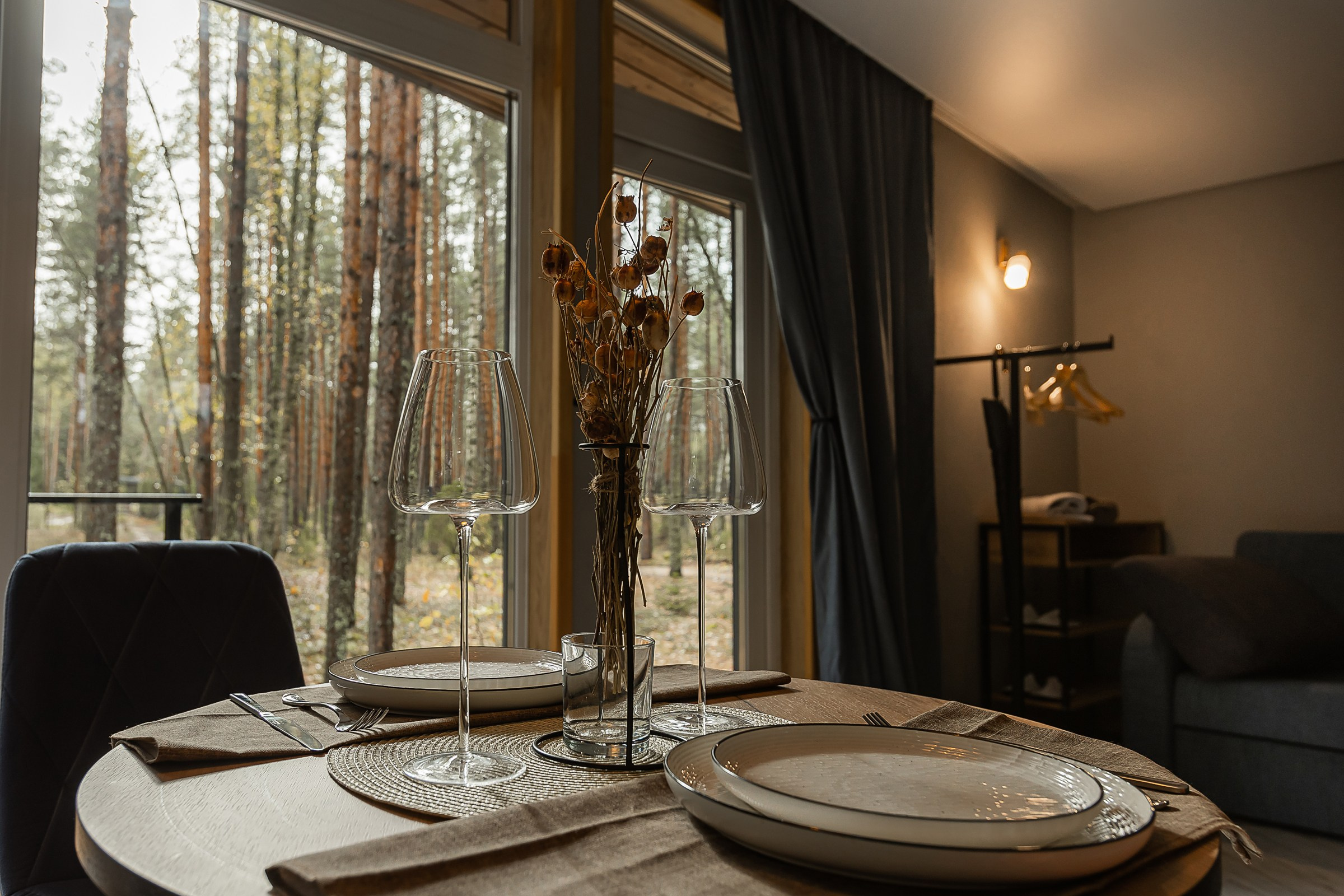 Бокалы на сервированном столе на фоне панорамных окон в загородном доме