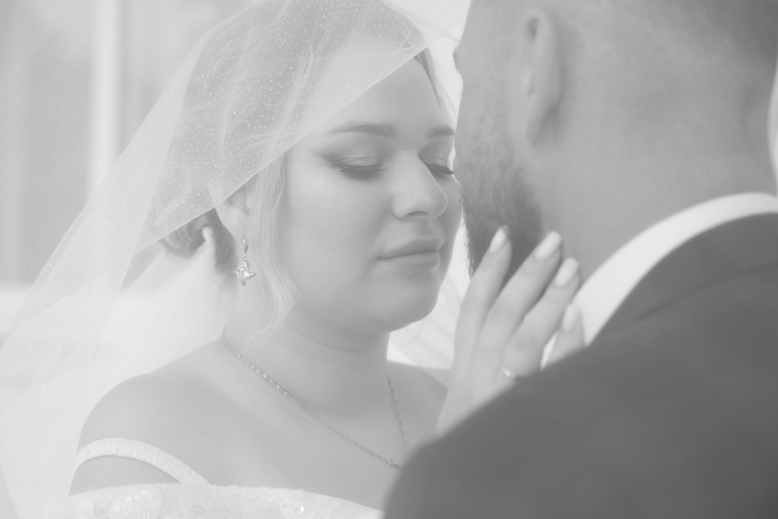 Невеста, закрытая фатой, нежно трогает жениха.