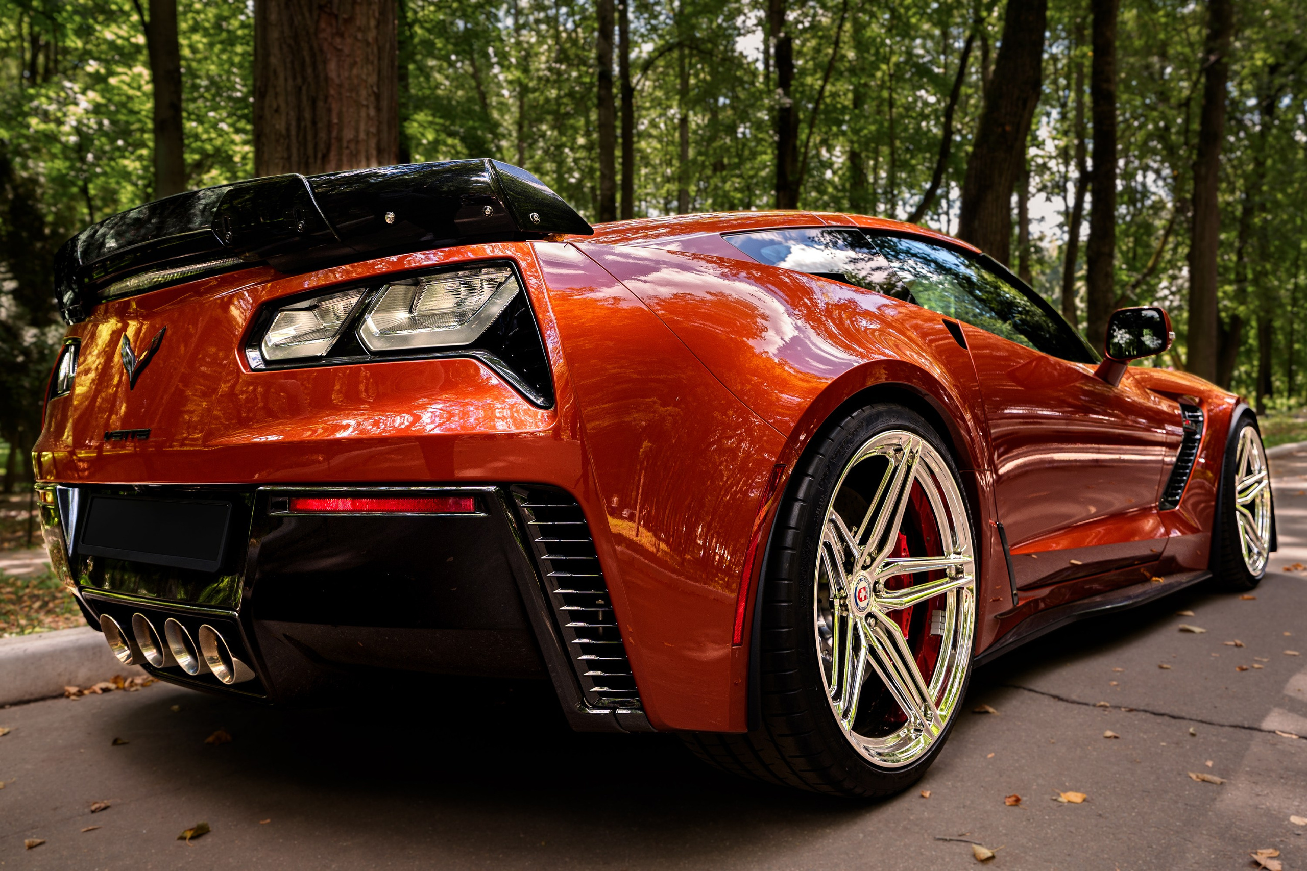 Фотосъёмка Chevrolet Corvette C7 Z06: задний ракурс оранжевого спорткара, кузов, колёса и спортивные детали.