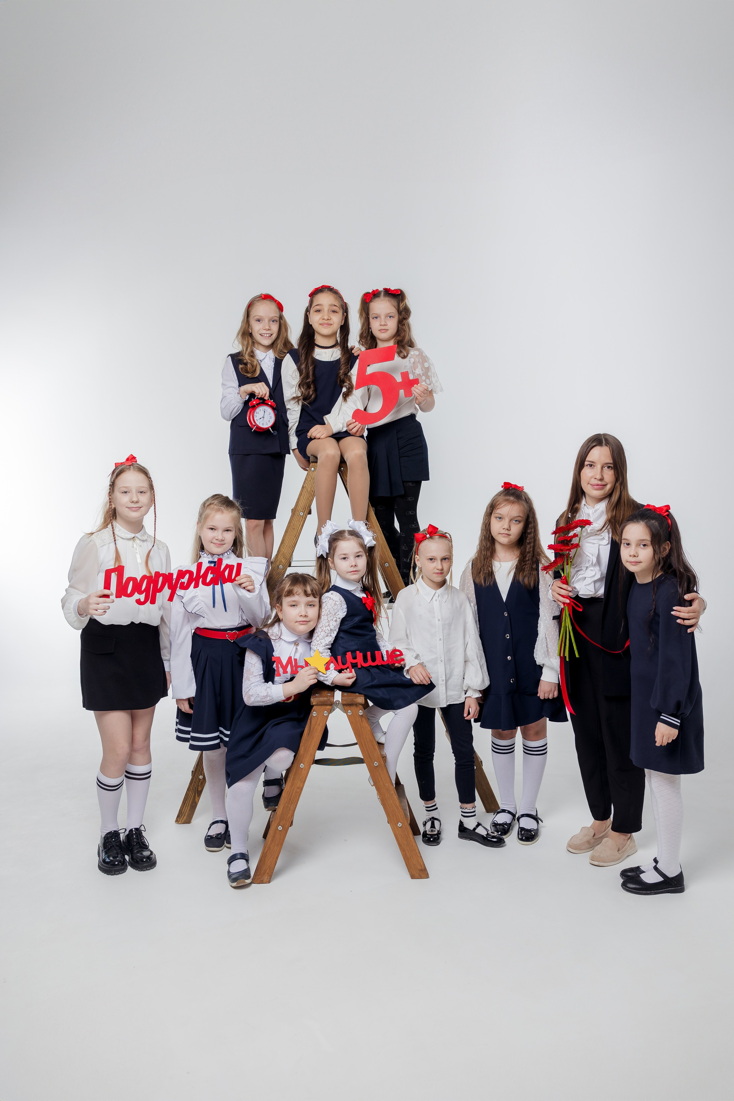 Девочки стоят с учителем на деревянной лестнице