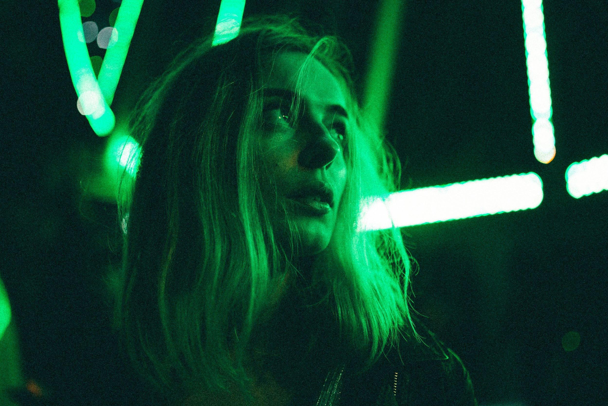 Девушка с каре смотрит на зеленую неоновую вывеску