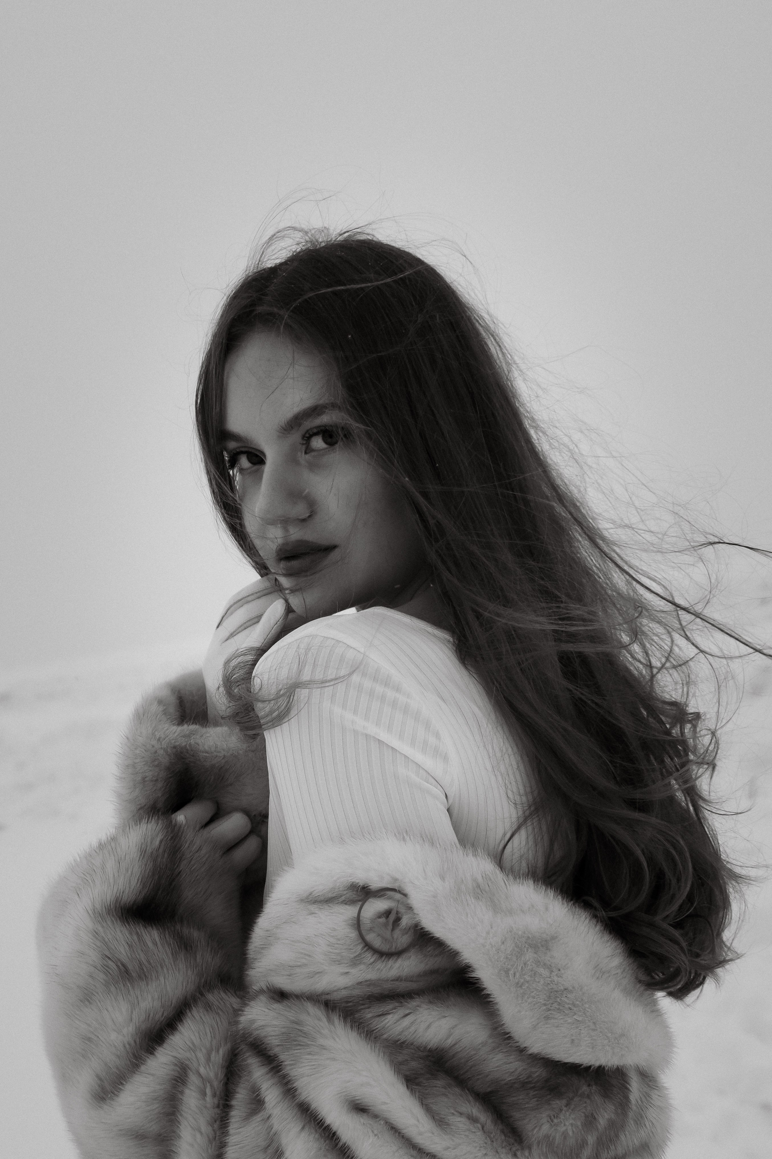 индивидуальная фотосессия в чб. Красивая девушка в шубе на фоне снежного поля