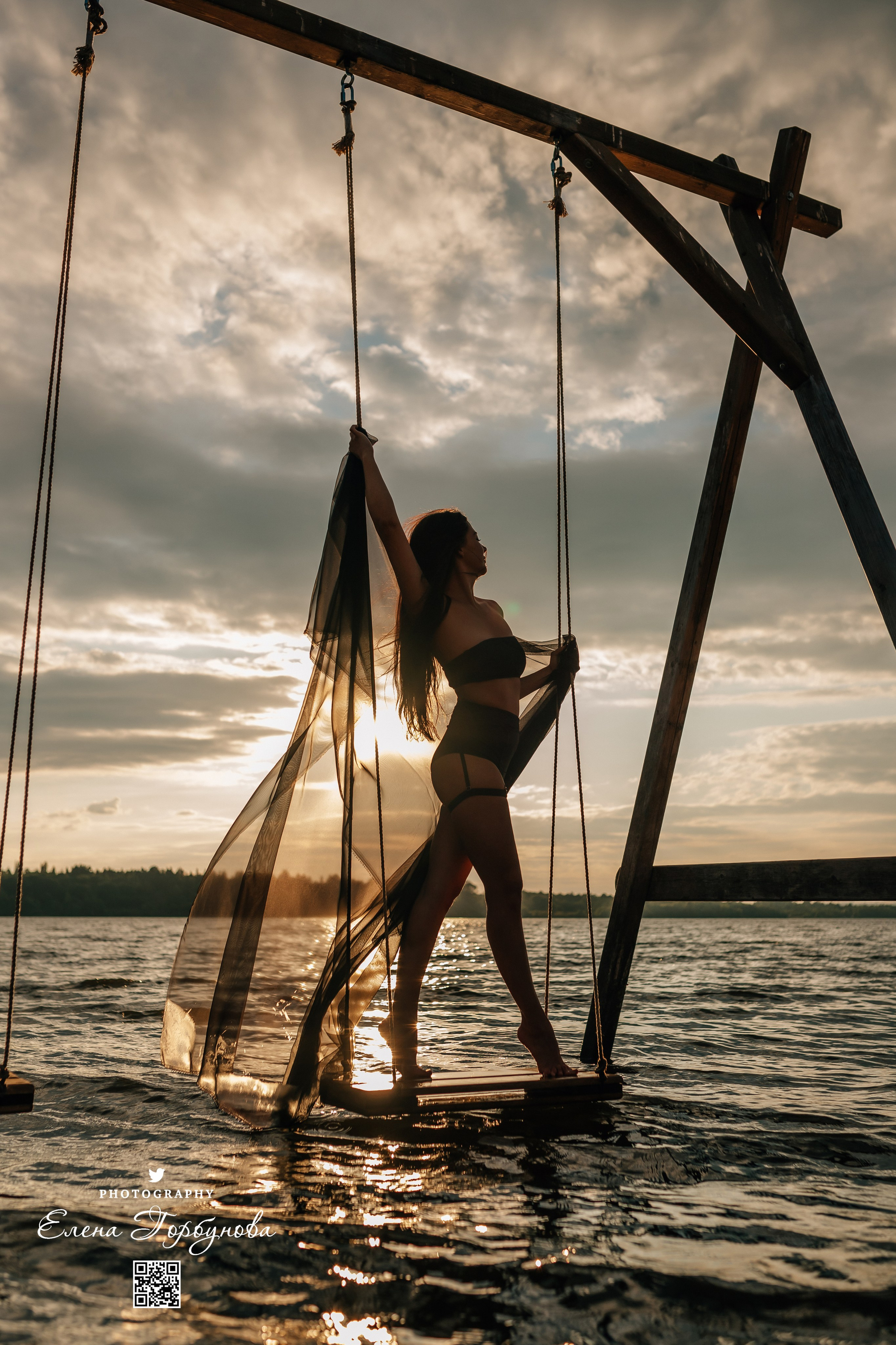 Фотосессия с черной тканью. Легкая черная вуаль летит на вертру. Фотосессия у реки черная серия с тканью. Девушка укуталась в черную ткань. Прогулка по набережной. Песок, речка, модель в черном. Качели над водой, Закат.