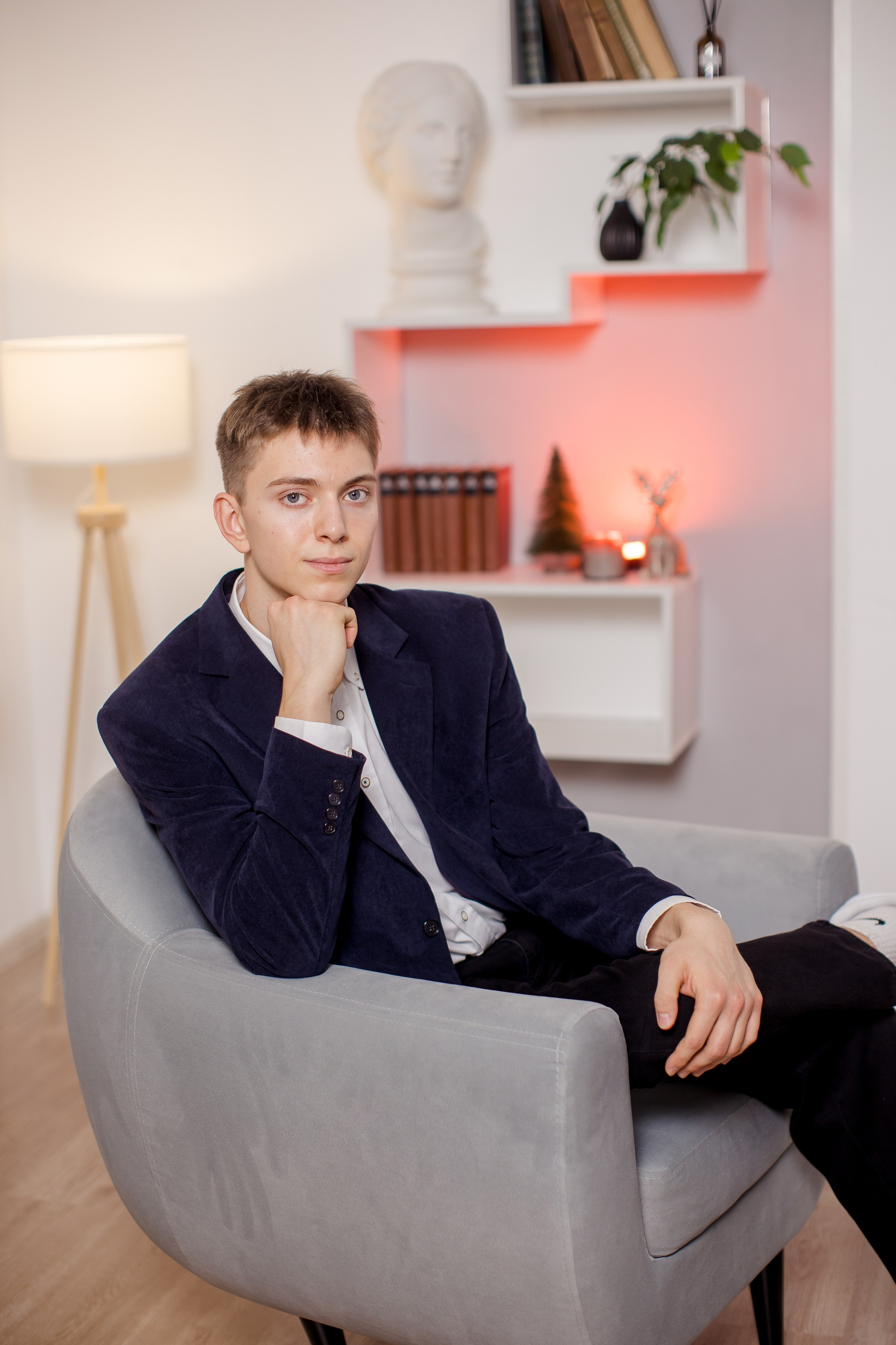 Молодой человек сидит в кресле в фотостудии