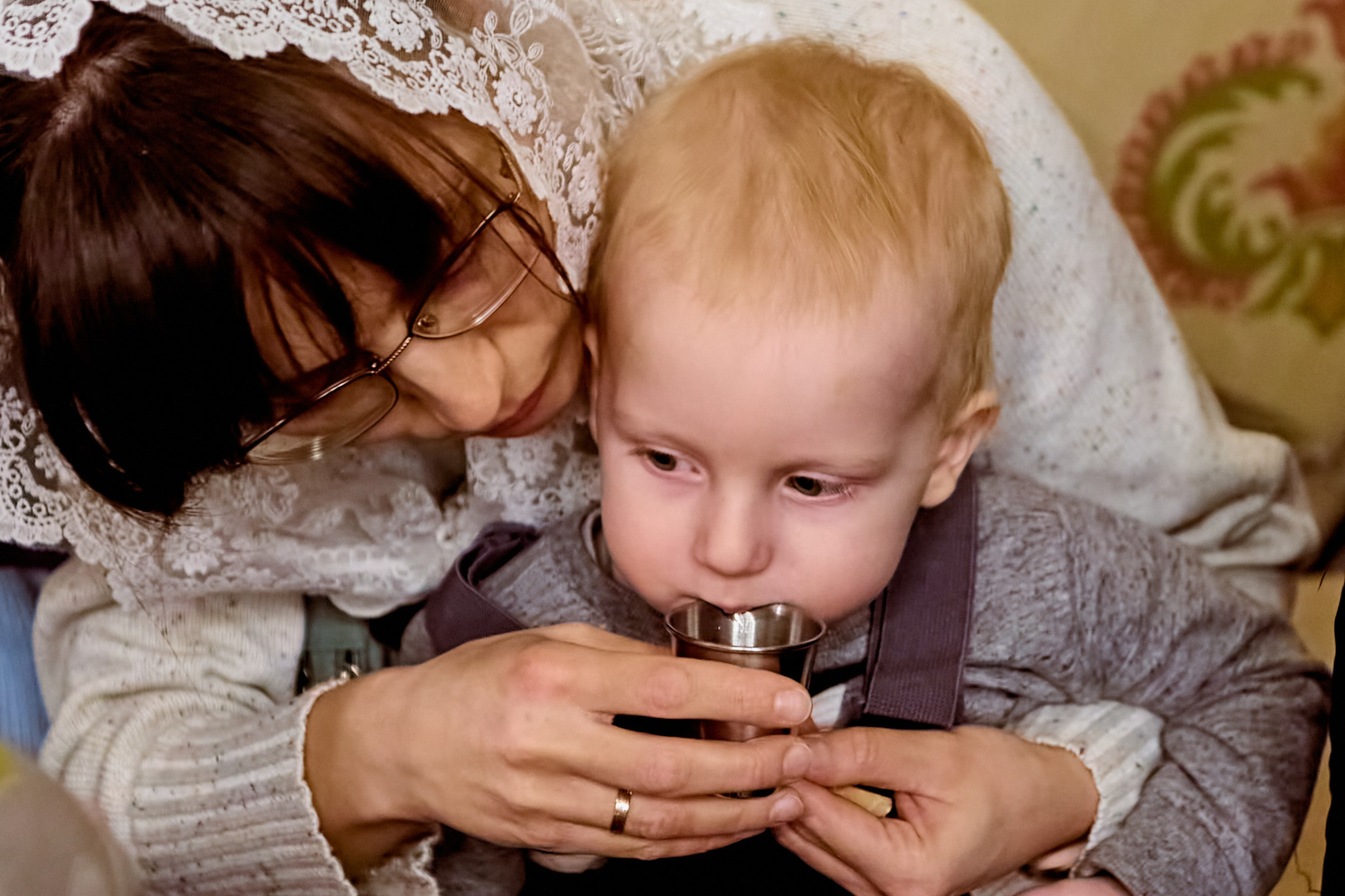 Мама с маленьким Федей на руках после причастия пьют водичку