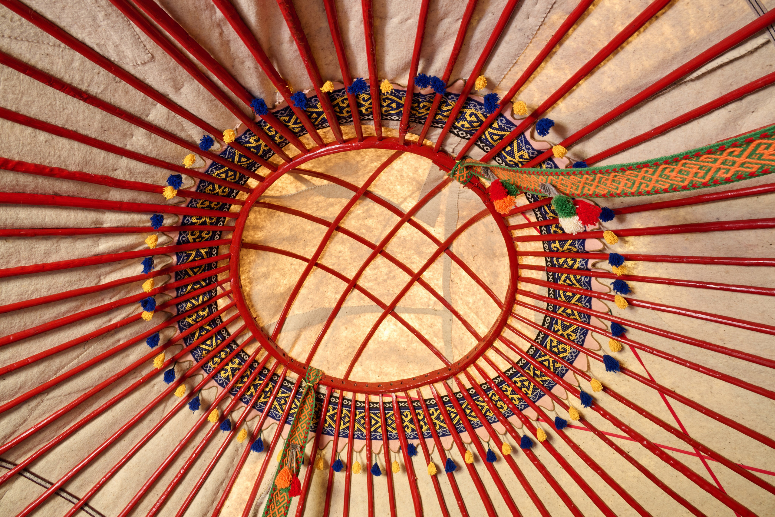 Верхняя часть юрты с видом на деревянный каркас и узорчатую подкладку, создающую уникальное сочетание культурной архитектуры и искусства.