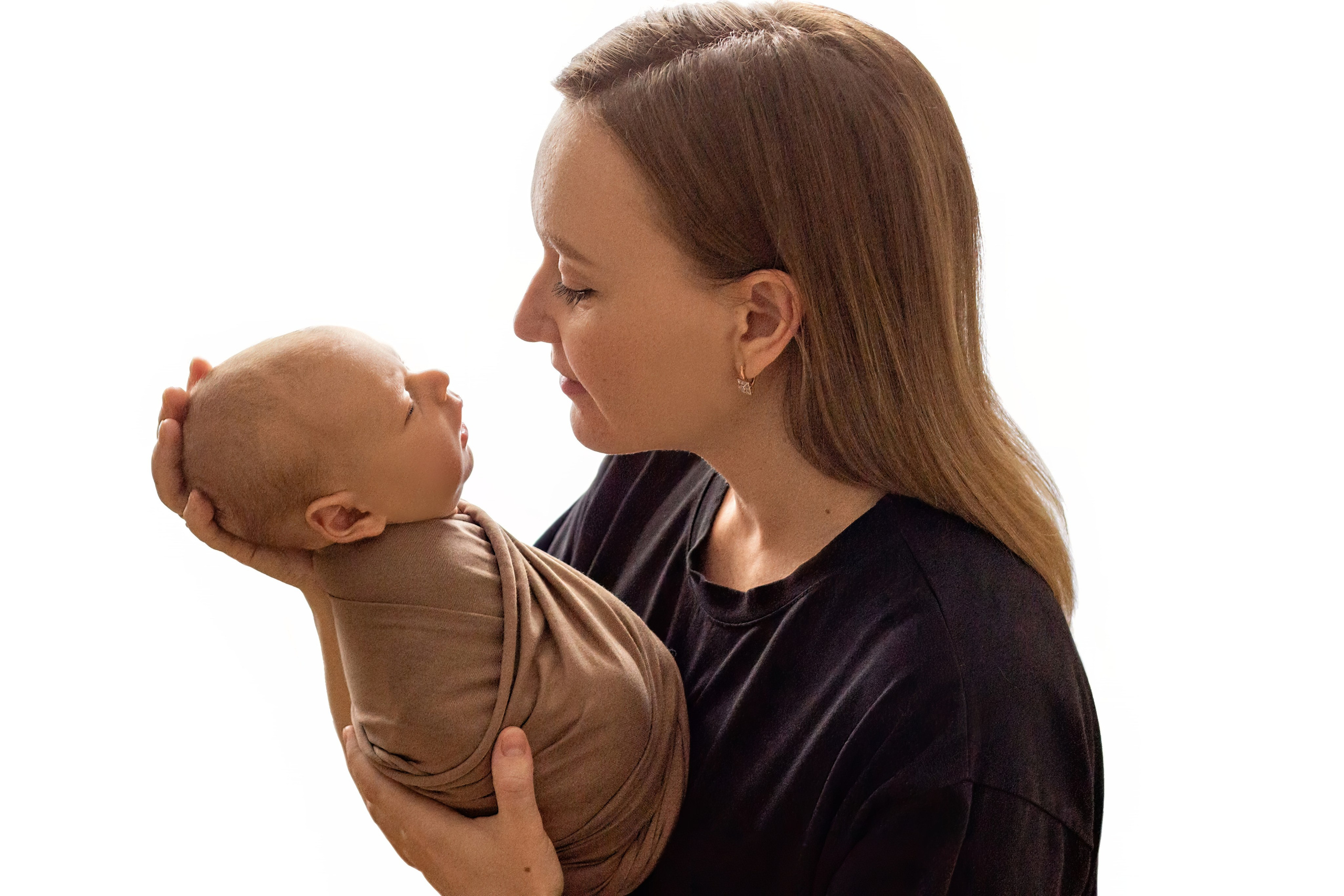портрет молодой мамы в черной футболке с укутанным в бежевую ткань малышом на руках на белом фоне, верхний ракурс