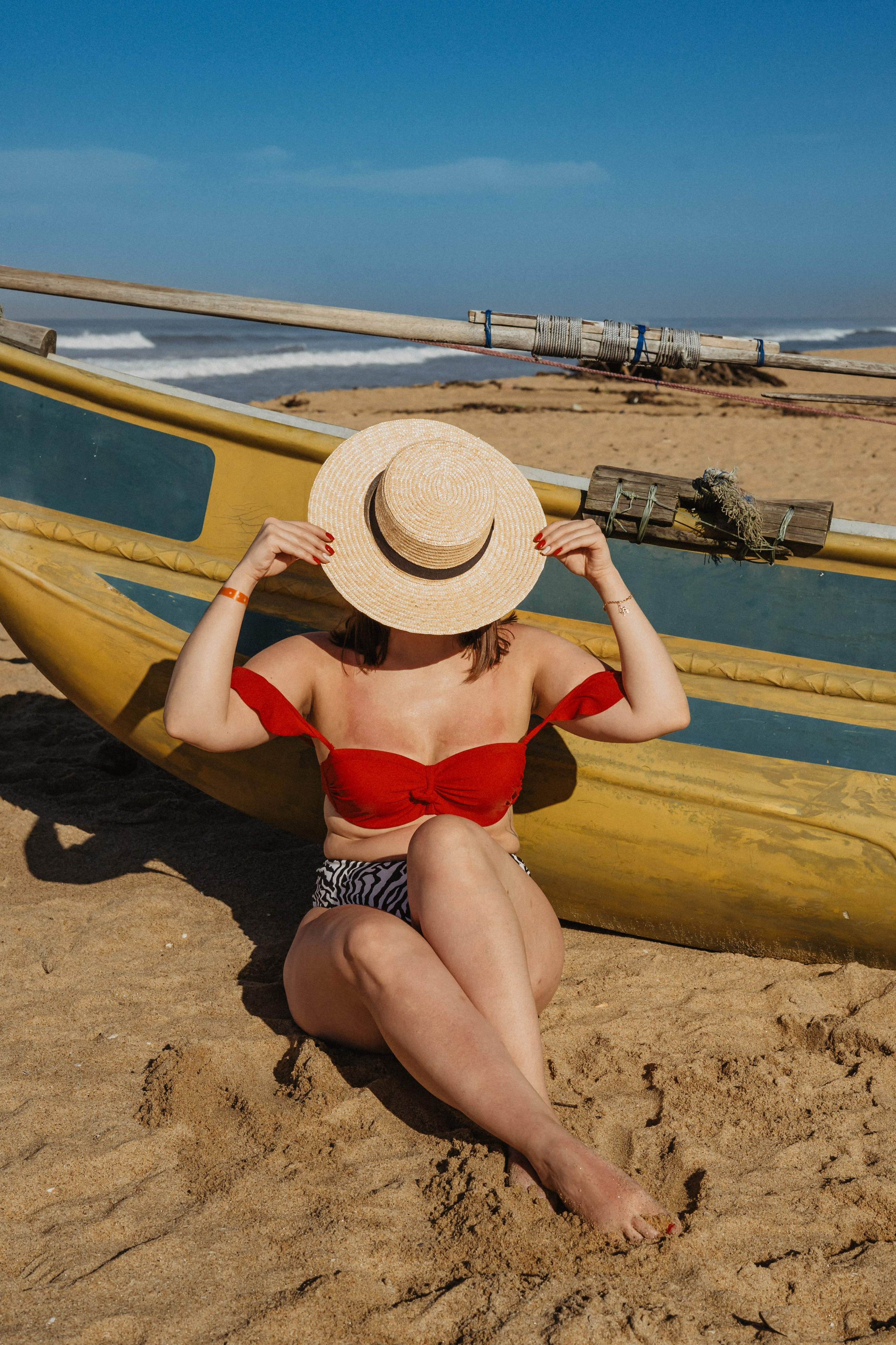 a girl in a straw hat with windblown hair on the beach