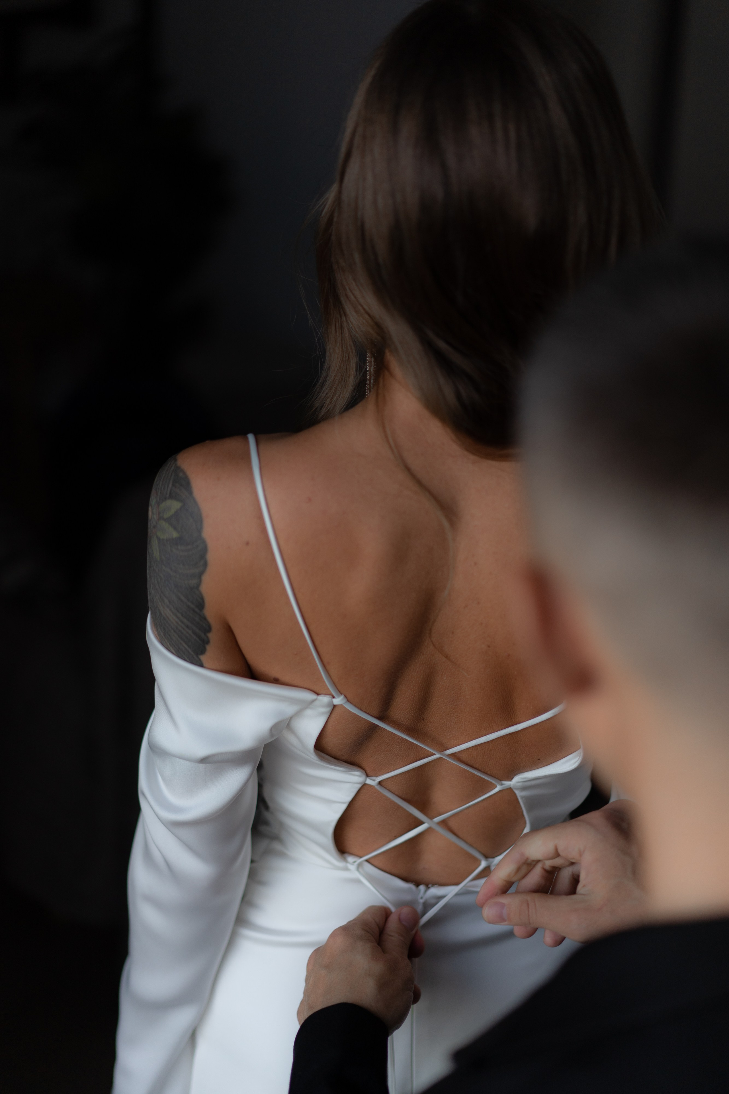 Жених затягивает корсет на спине у невесты