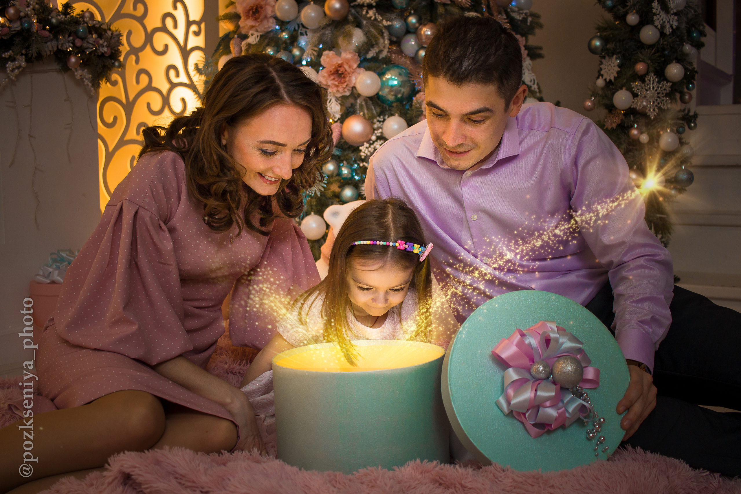 Новогодняя семейная фотосессия, семья удивленно заглядывает в волшебную коробочку.