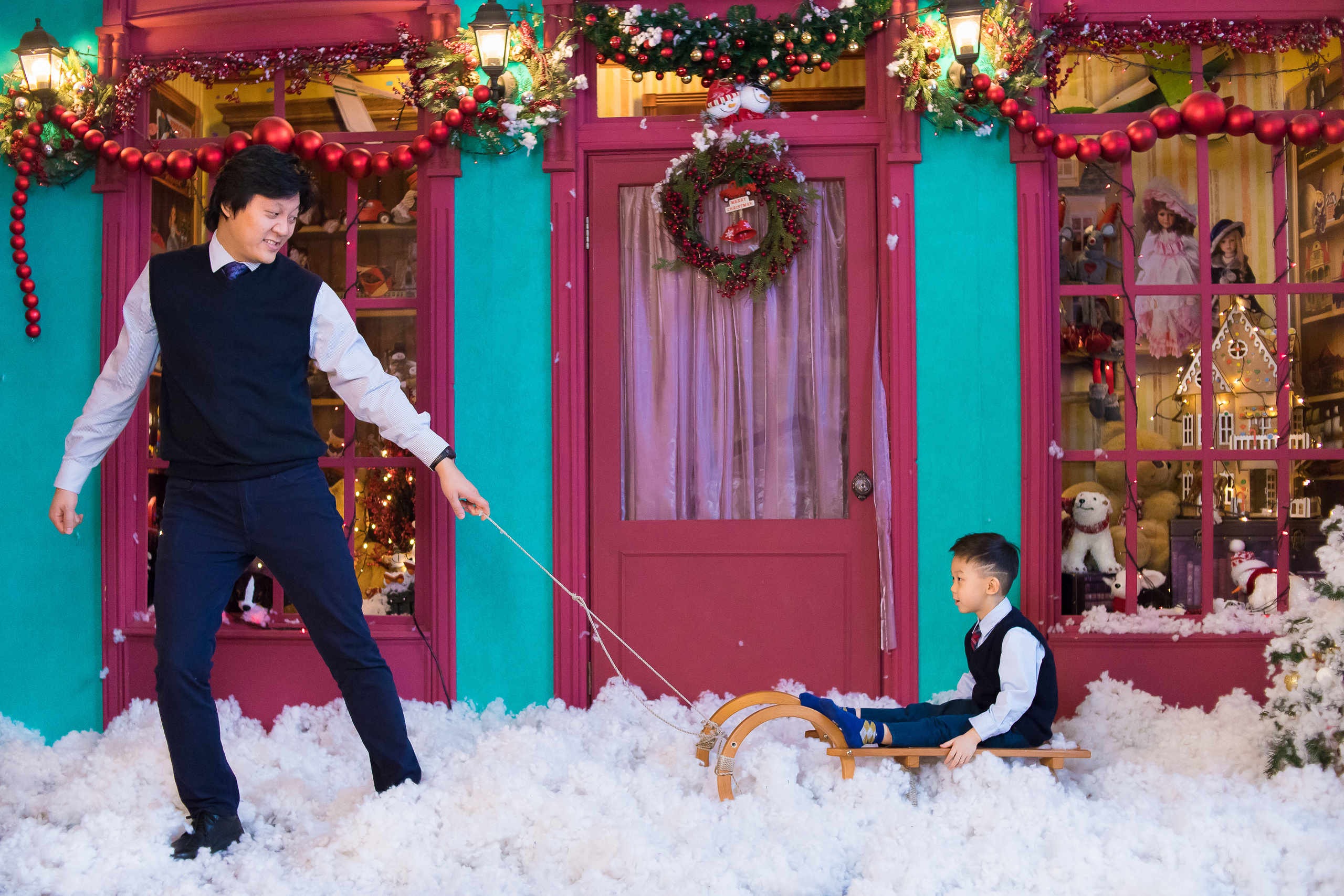 Папа и сын катаются на санках по искусственному снегу в студии.