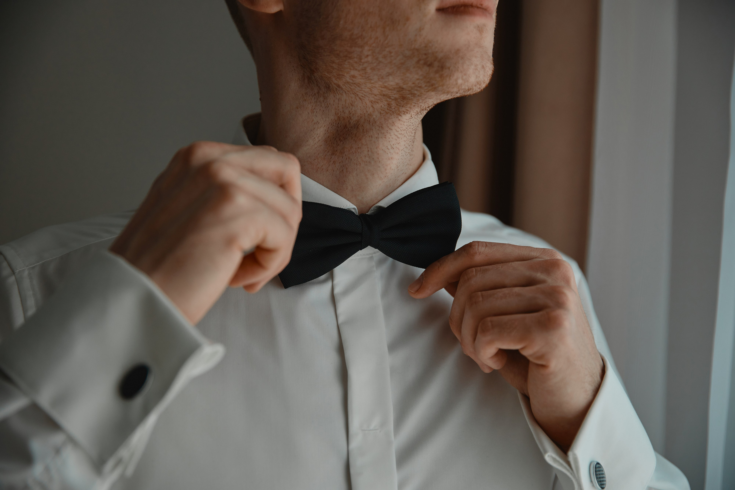 Жених поправляет бабочку на фотографии