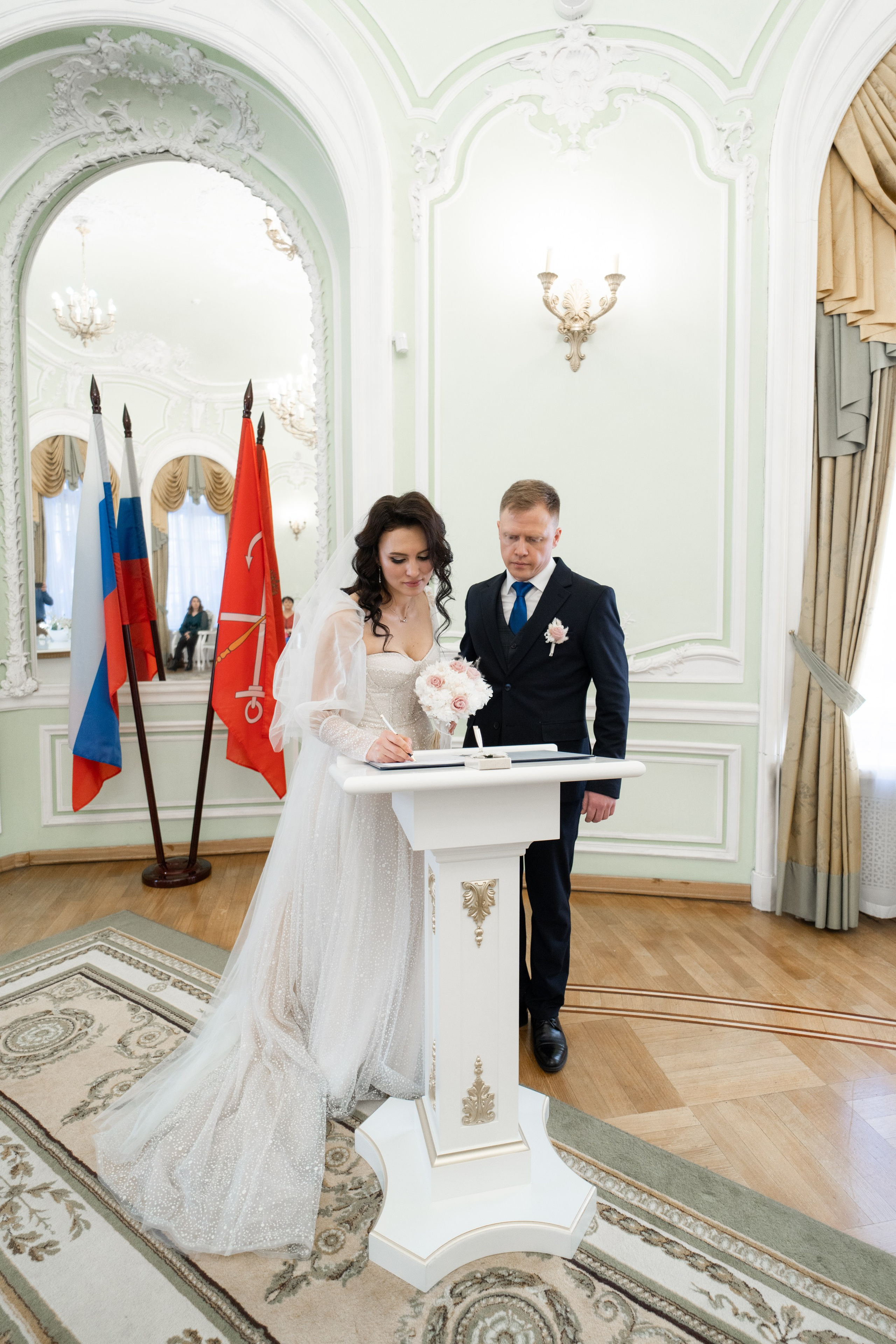 Жених и невеста ставят подписи в зале торжественной регистрации загса Петроградского района