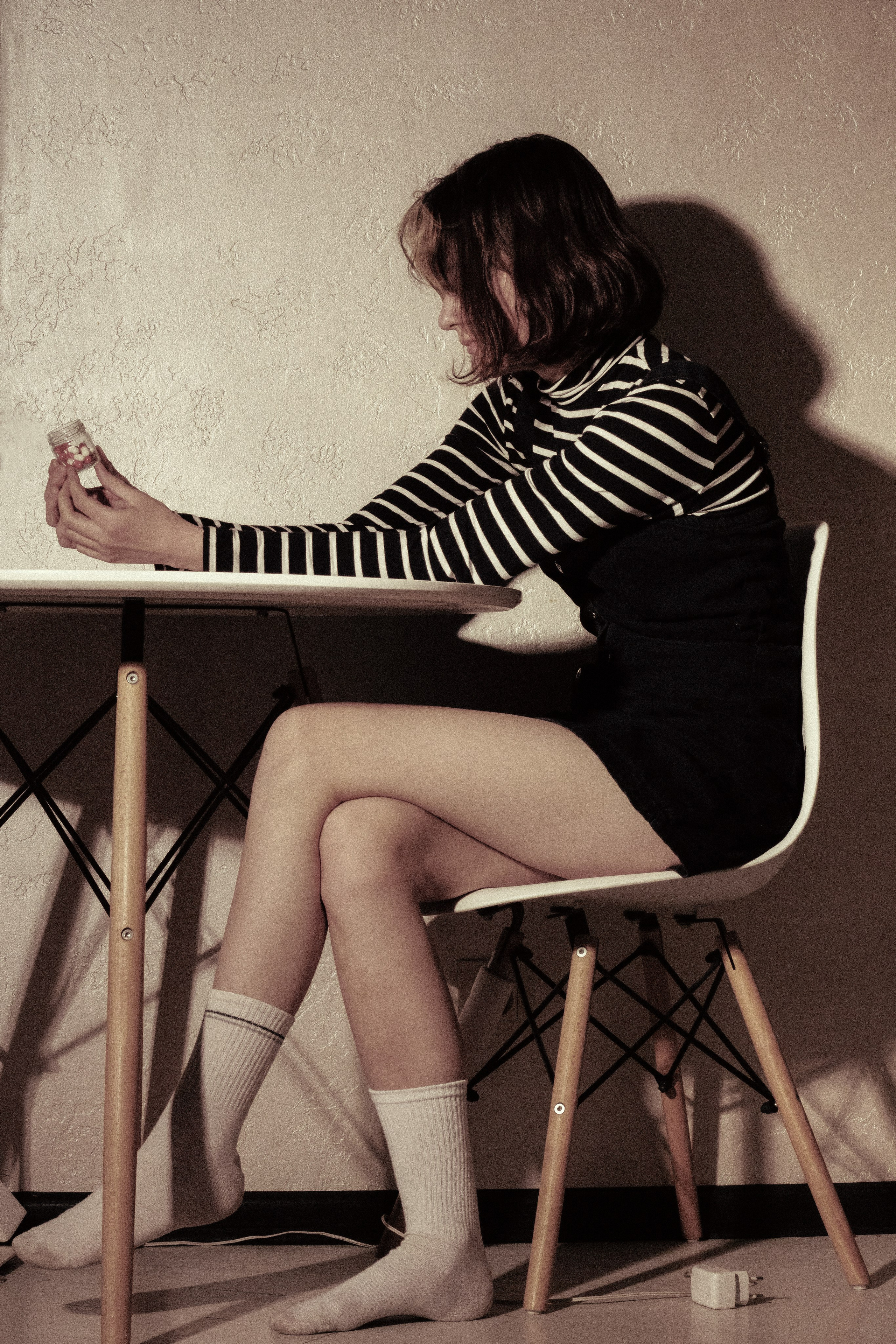 Девушка сидит за столом в тусклом свете, в руке баночка с успокоительным — в голове пустота после потери.