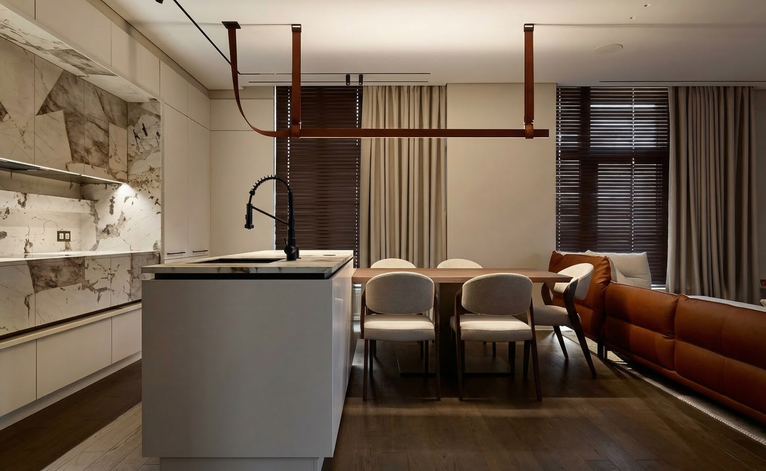 Современная кухня-гостиная с белым островом, мраморным фартуком и уникальным линейным светильником на кожаных подвесах.