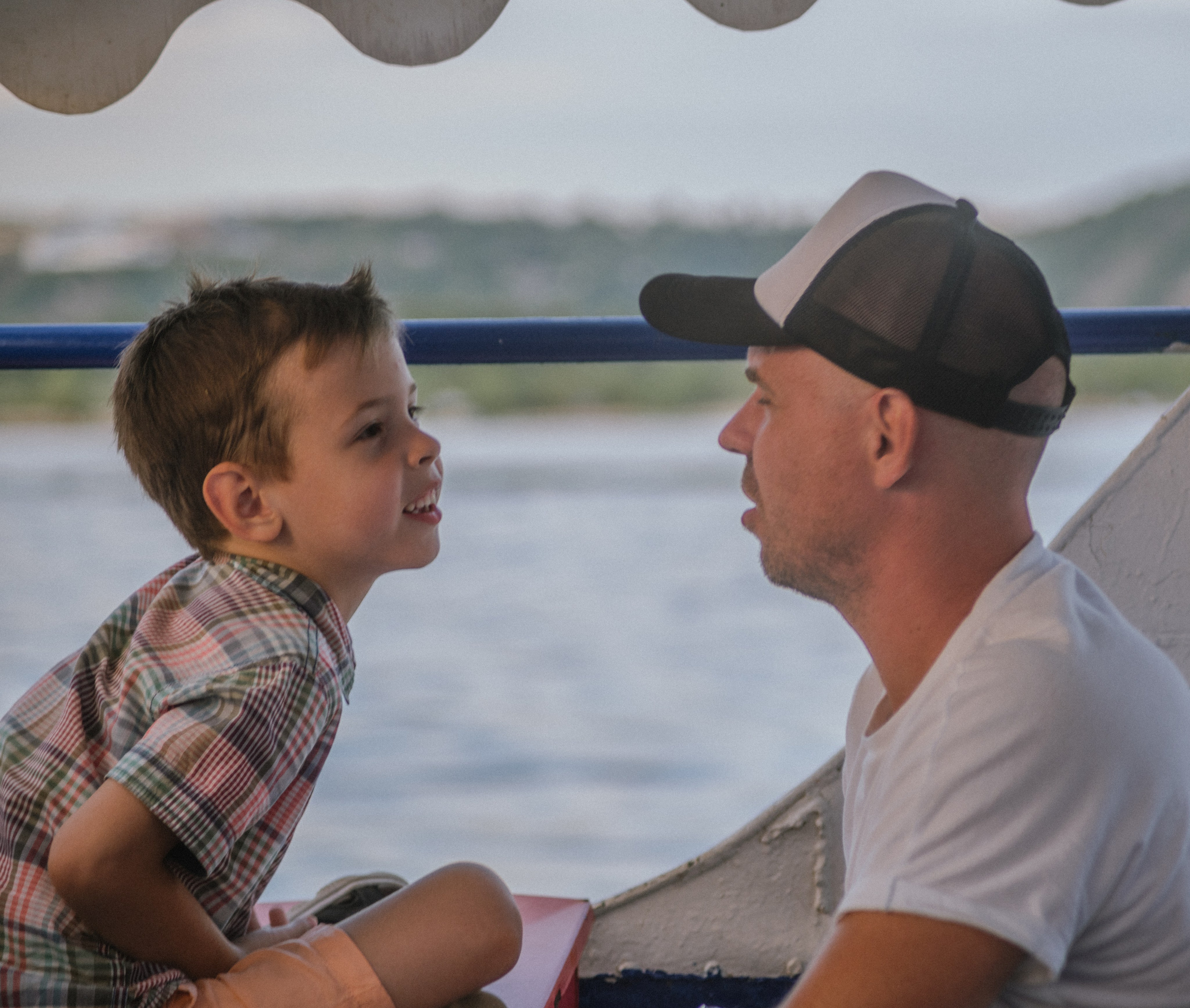 Отец и сын снова встречаются взглядами, сидя напротив на лодке — глубокая связь и душевная теплота в одном кадре.