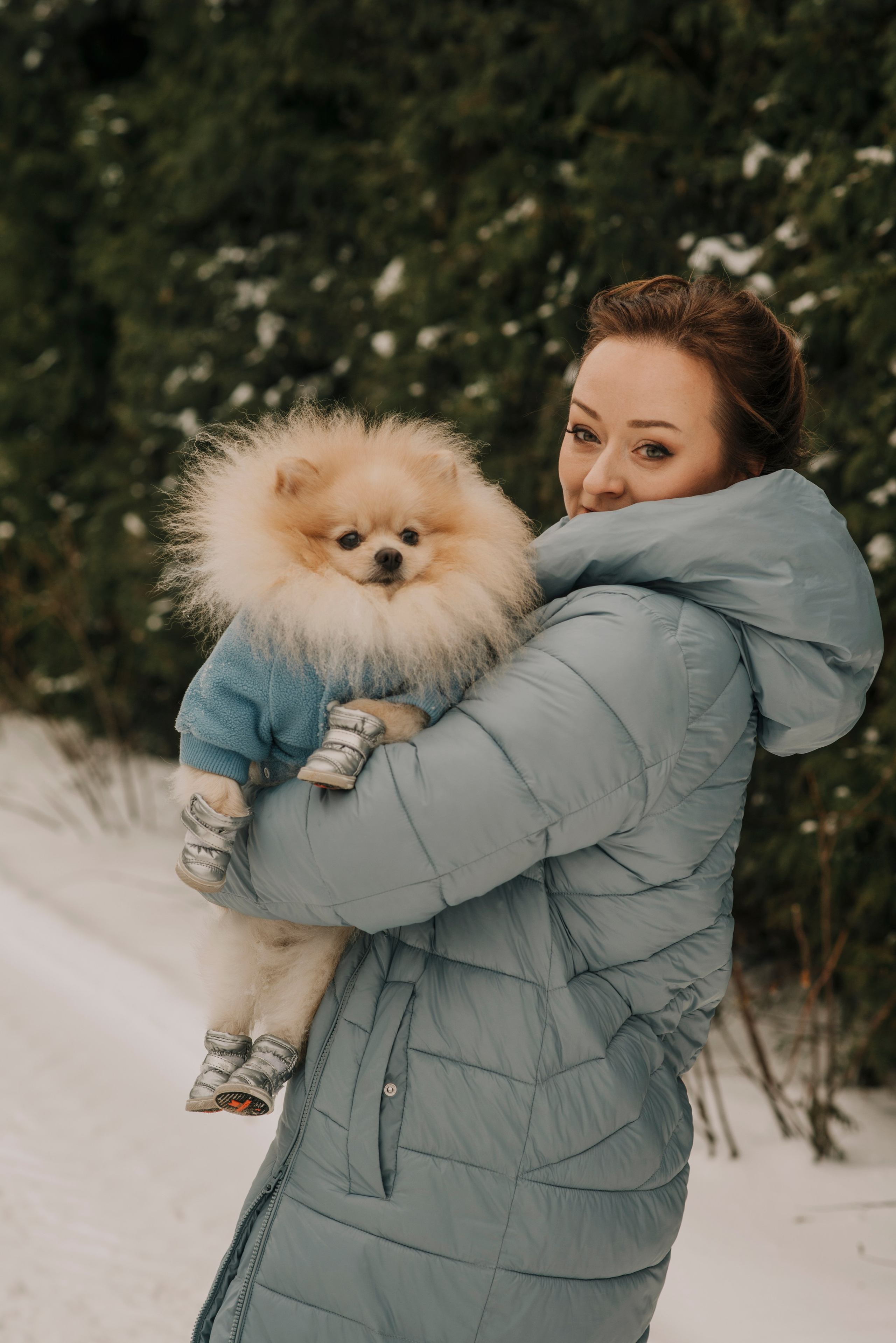 Девушка позирует на фоне леса с рыжей собакой шпицем