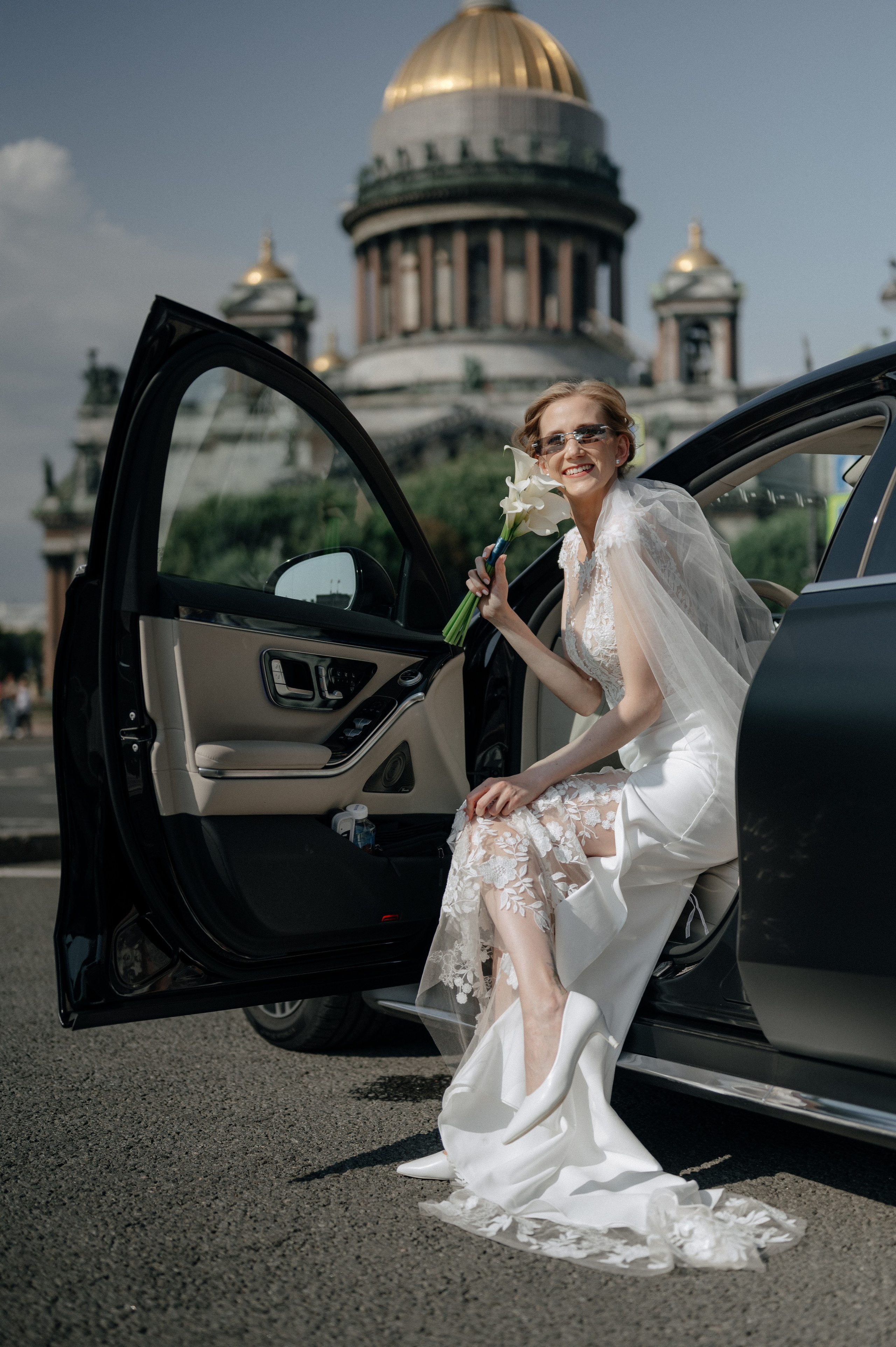 Невеста сидит в автомобиле на фоне Исаакиевского собора в Санкт-Петербурге
