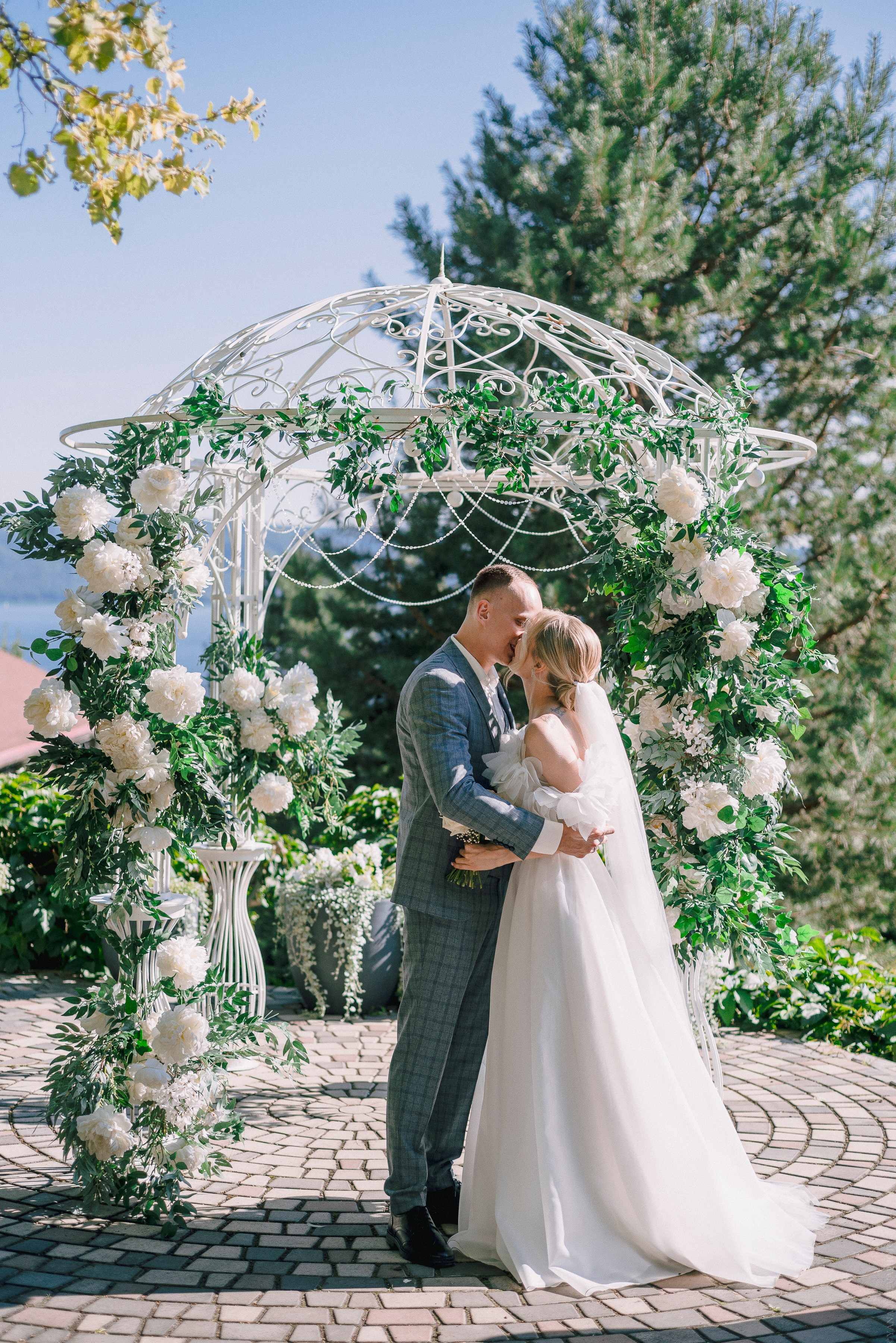 Жених и невеста целуются по аркой