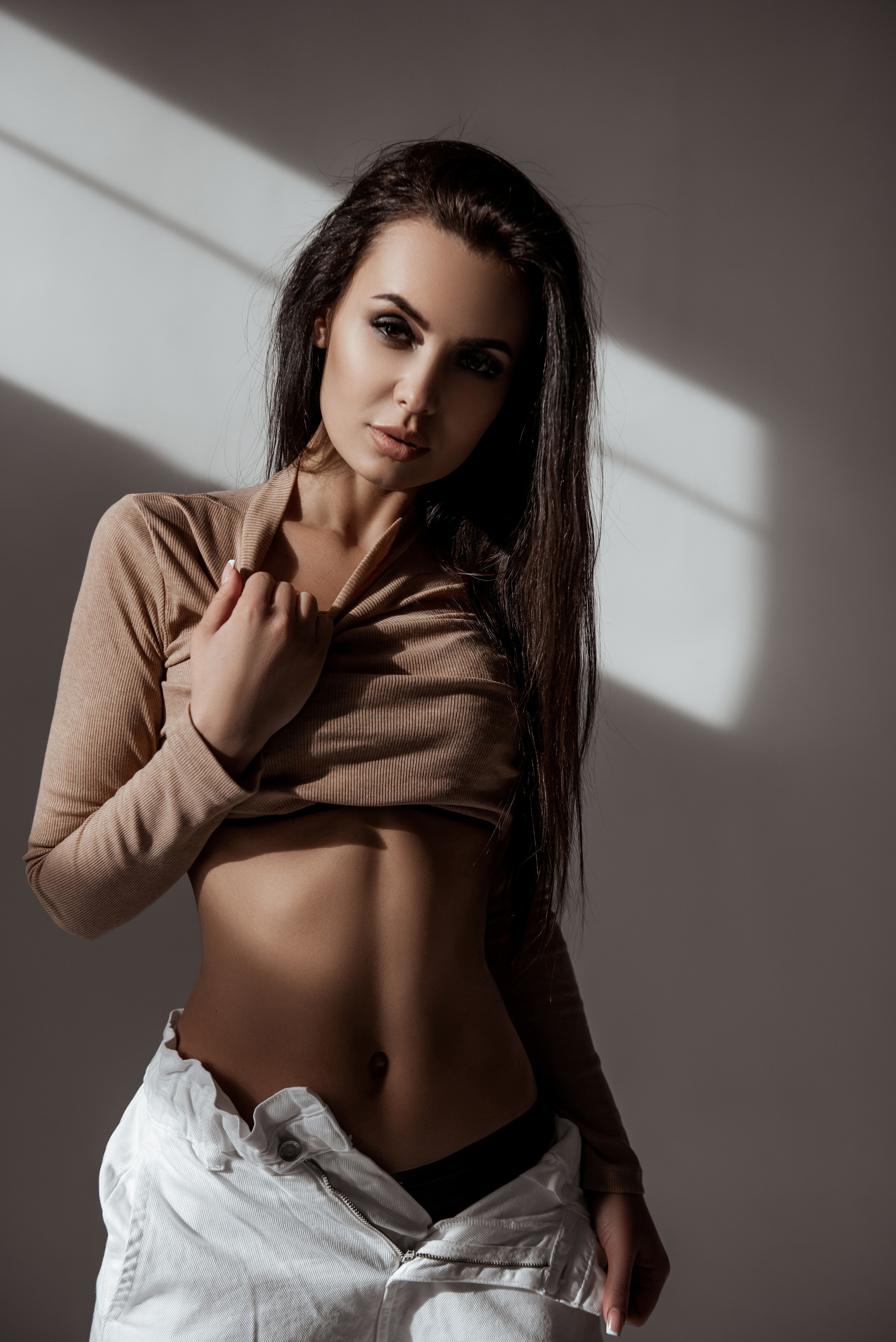 Фотография девушки в короткой водолазке и расстёгнутых белых штанах