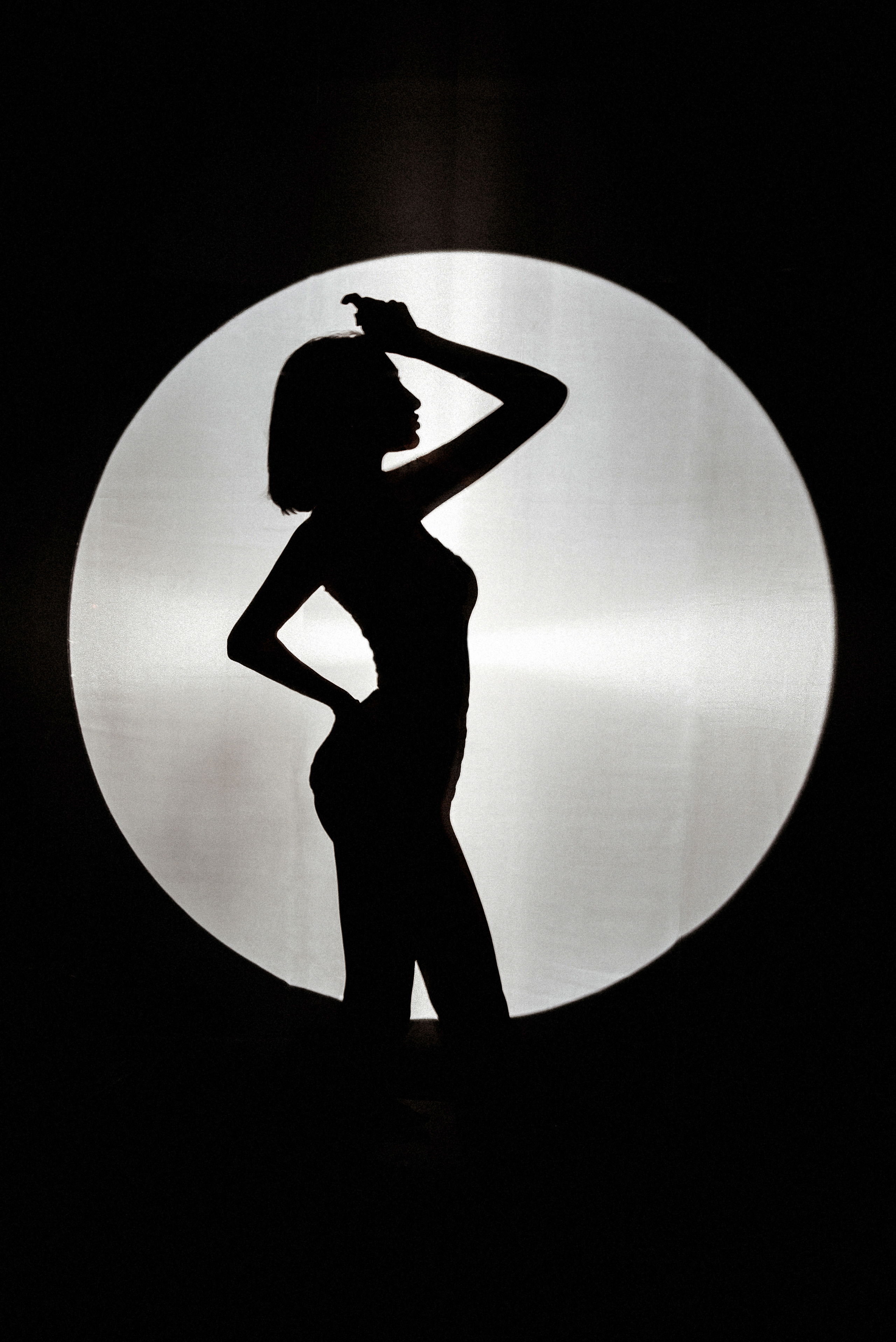 Силуэт красивой девушки, тень на стене в свете прожектора