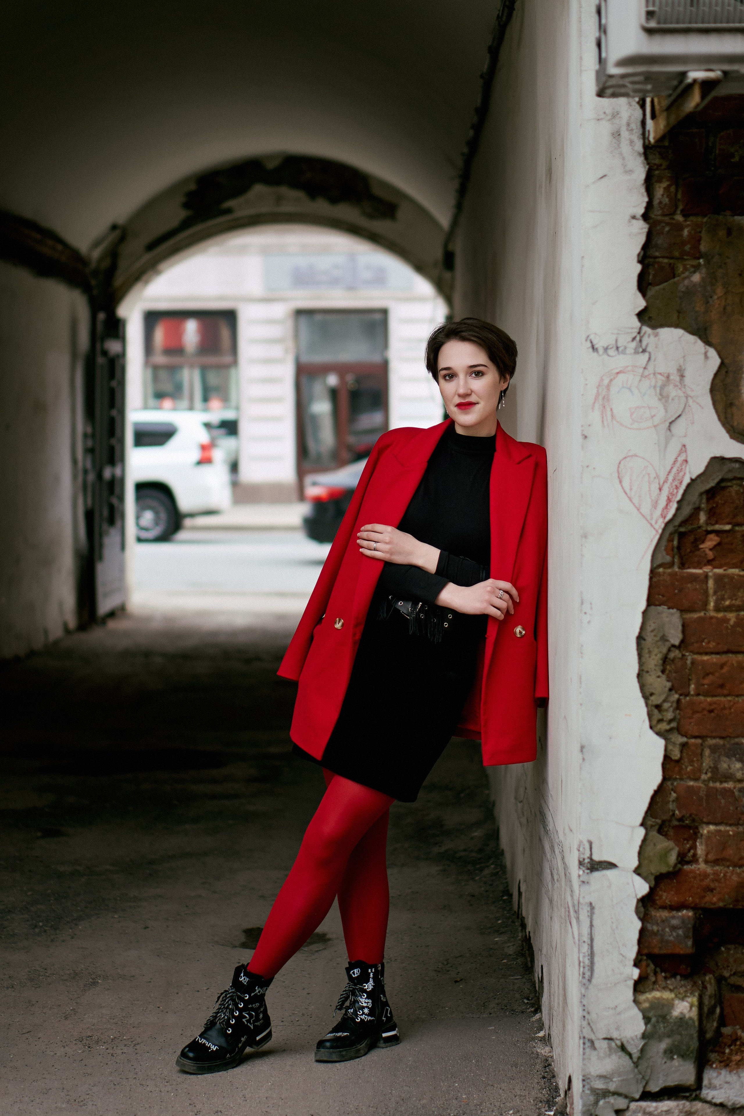 Девушка в красном пиджаке стоит в арке