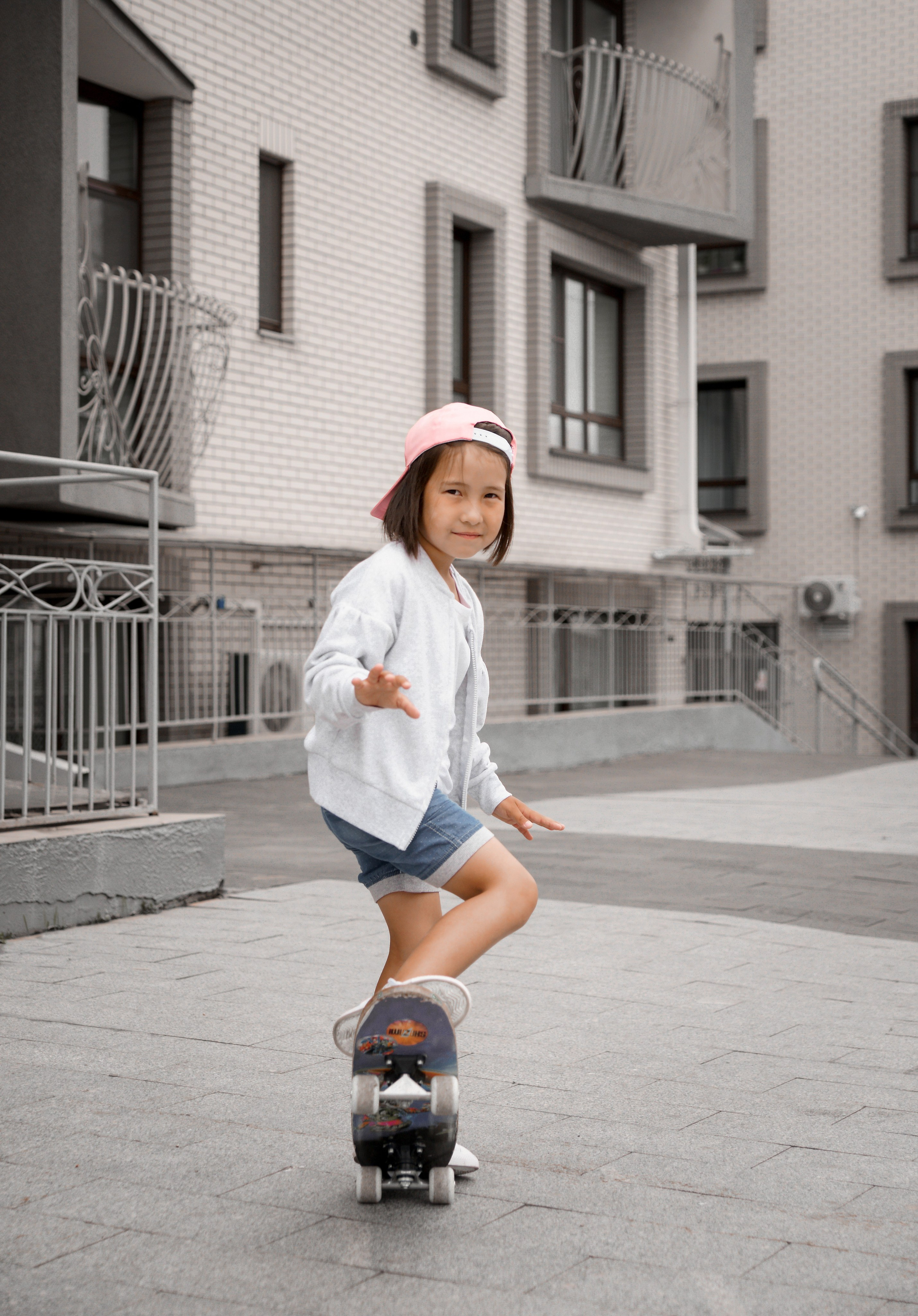 Детская фотосессия летом - девочка стоя в бейсболке на скейте