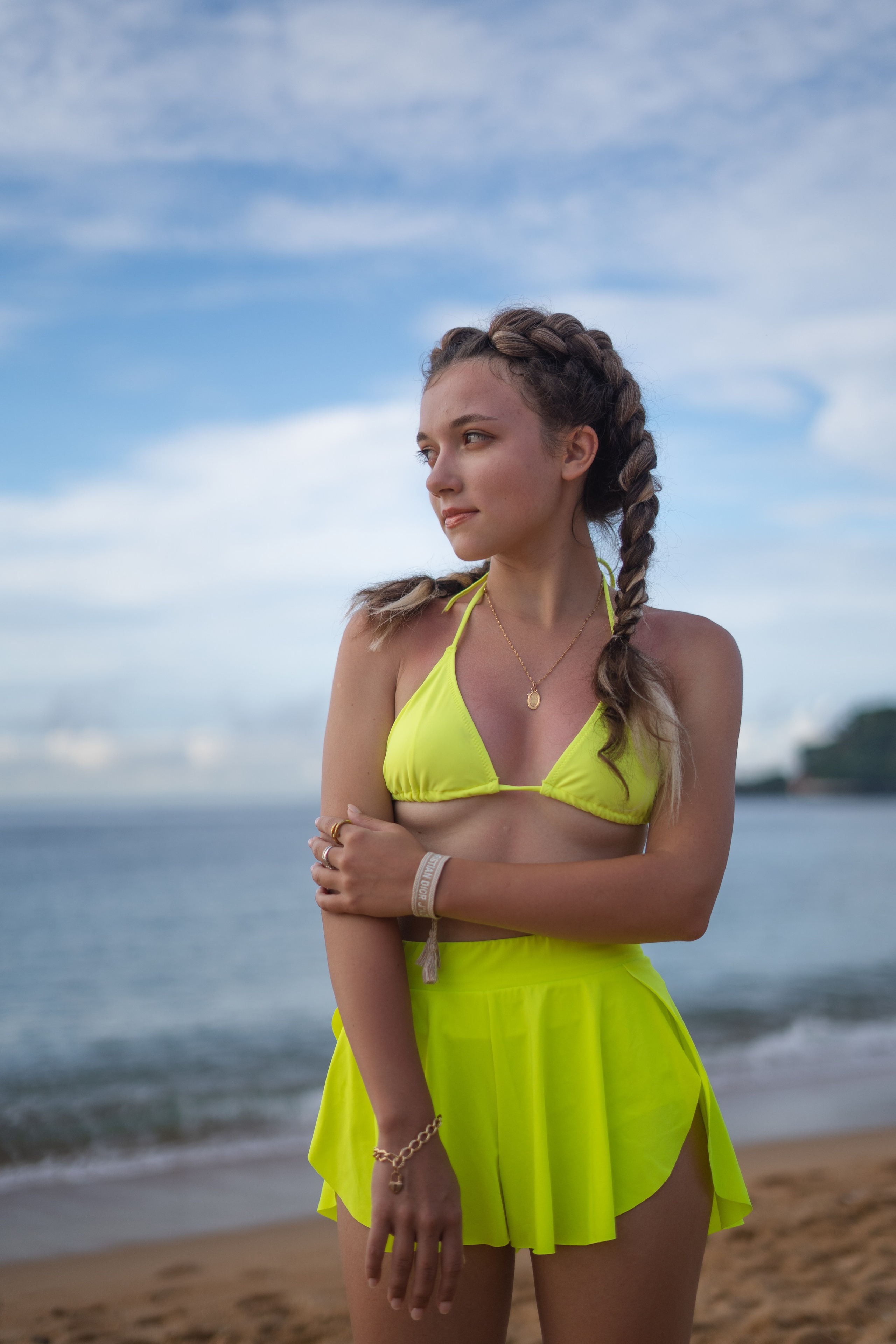 a girl with braids in a yellow swimsuit taking steps along the ocean shore